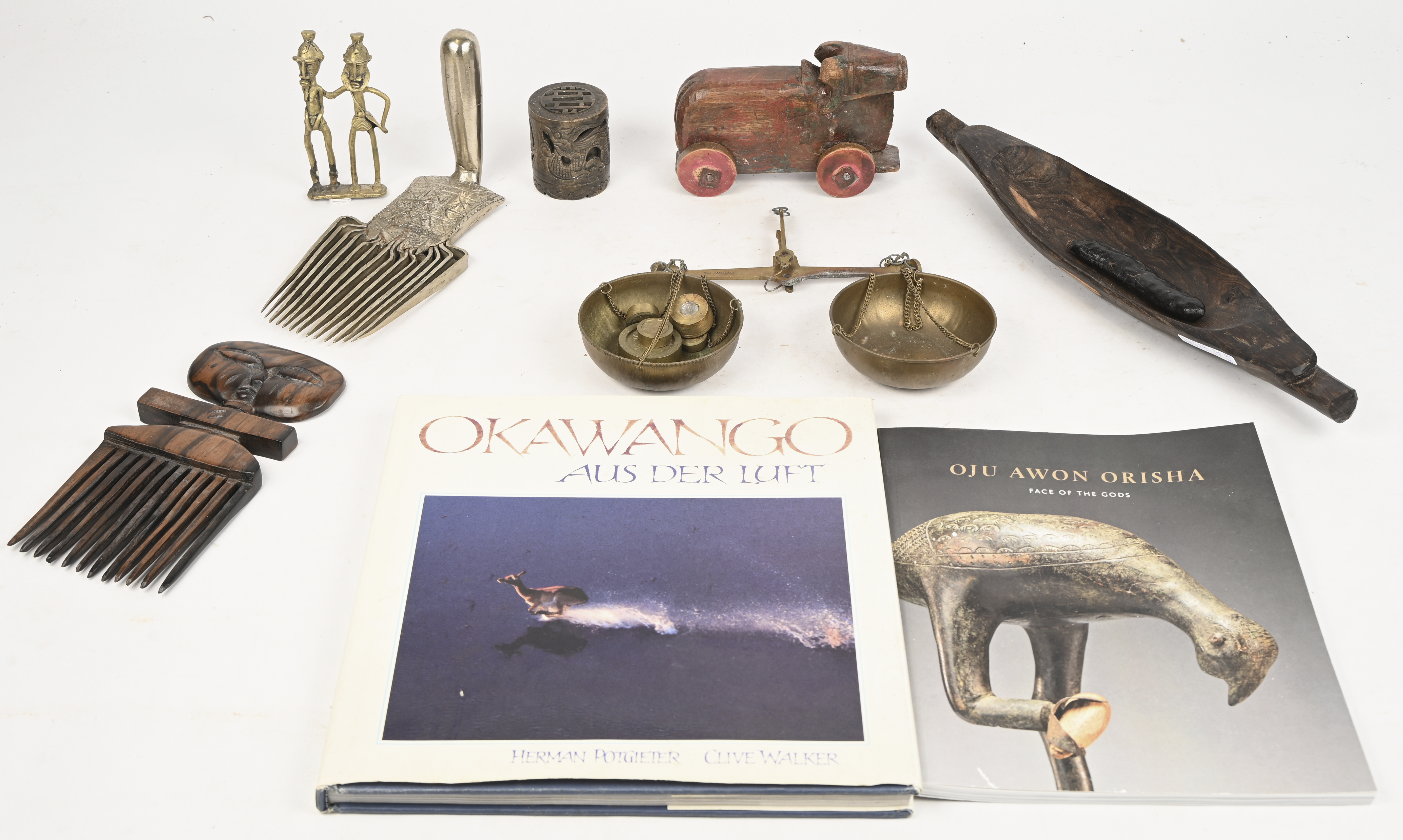 Een lot etnische voorwerpen bestaande uit 2 kammen; een houten os, een beeldje van een koppel, een bootvormig schaaltje, een rammelaar met zaden, een stenen potje met Aziatische draak, een koperen weegschaal met gewichtjes en toegevoegd 2 boeken Een lot etnische voorwerpen bestaande uit 2 kammen; een houten os, een beeldje van een koppel, een bootvormig schaaltje, een rammelaar met zaden, een stenen potje met Aziatische draak, een koperen weegschaal met gewichtjes en toegevoegd 2 boeken.