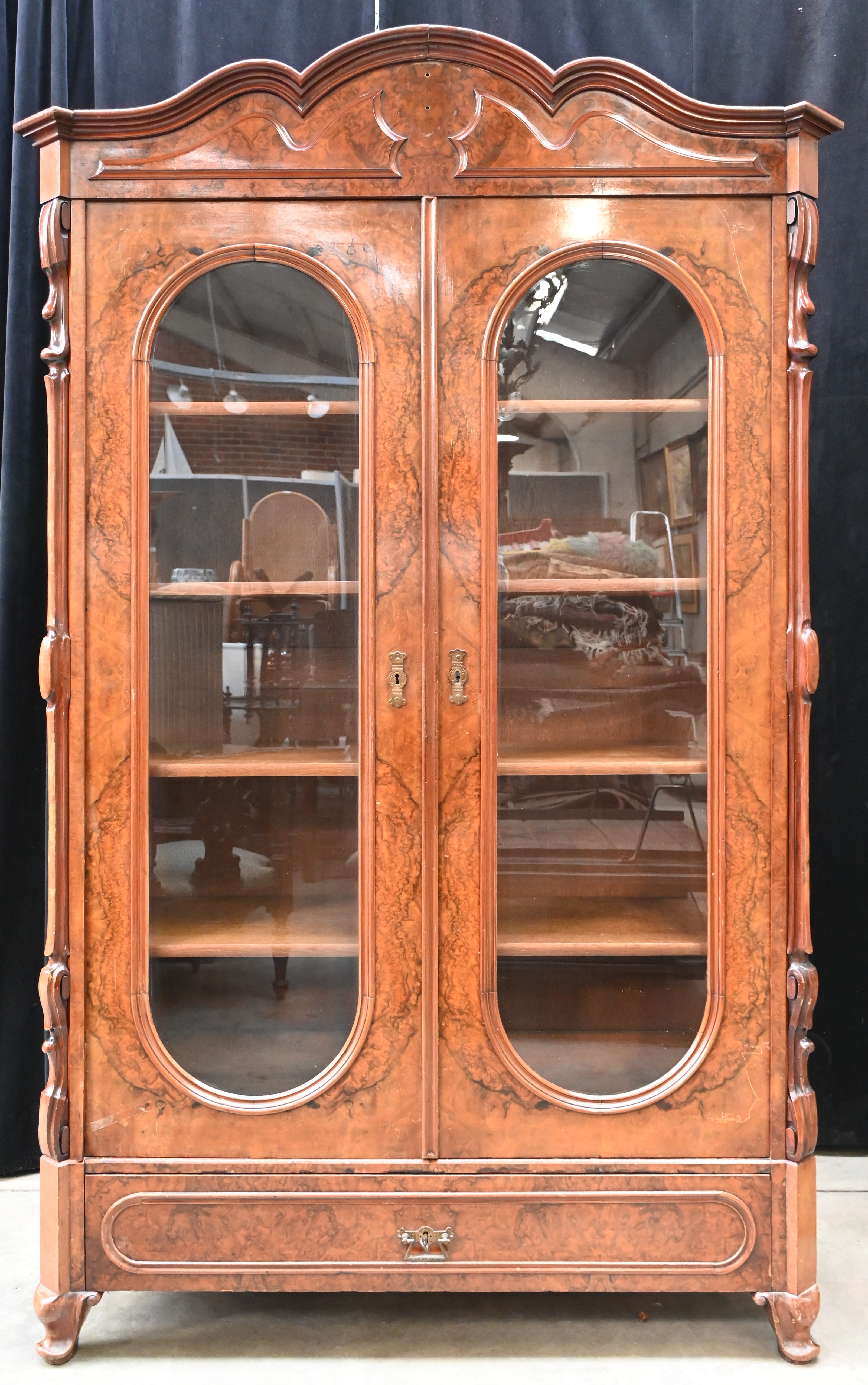 Een legkast met twee vitrinedeuren en onderaan één lade. Wortelfineer Een legkast met twee vitrinedeuren en onderaan één lade. Wortelfineer.