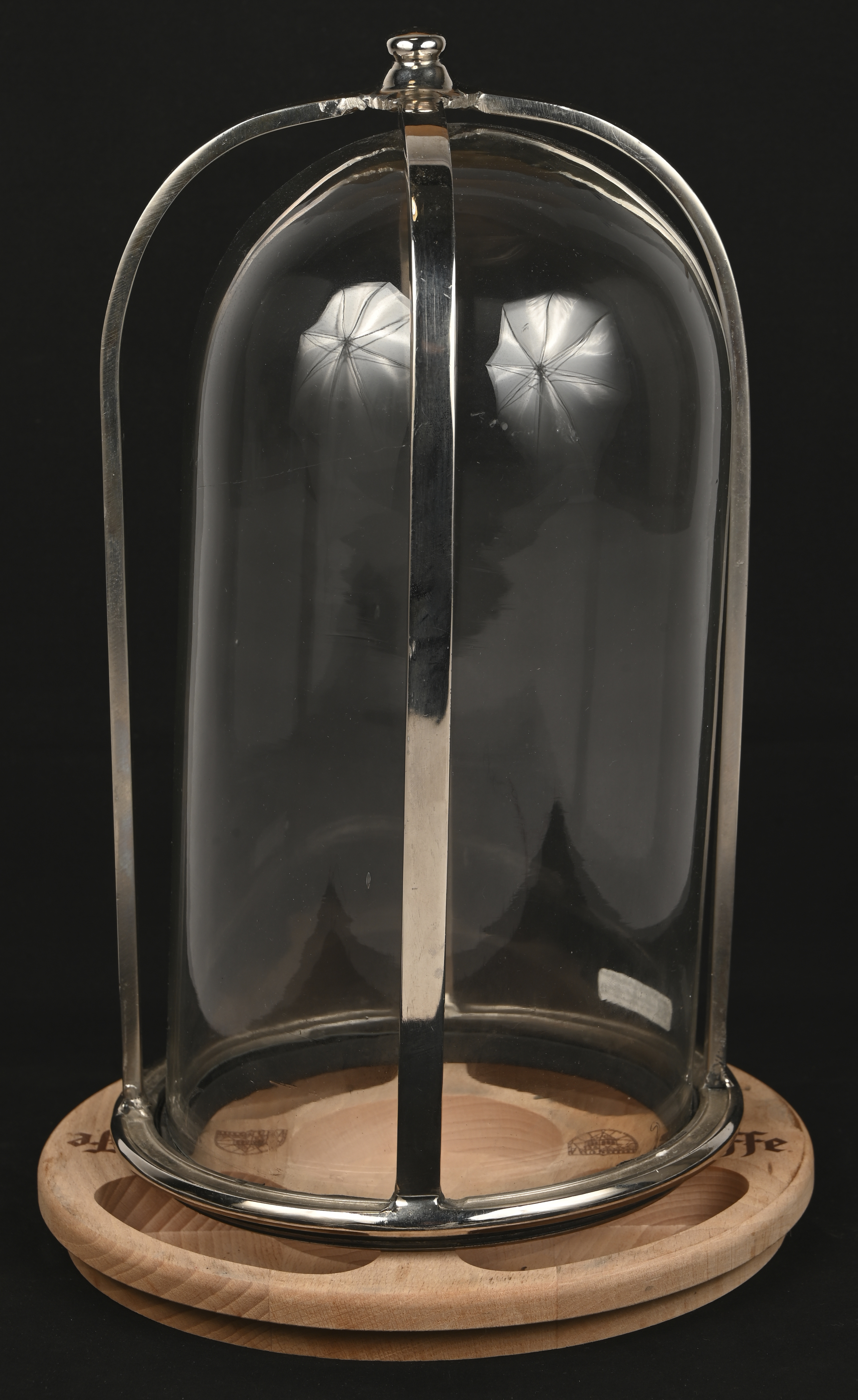 Een glazen stolp in metalen houder op houten voetje Een glazen stolp in metalen houder op houten voetje.