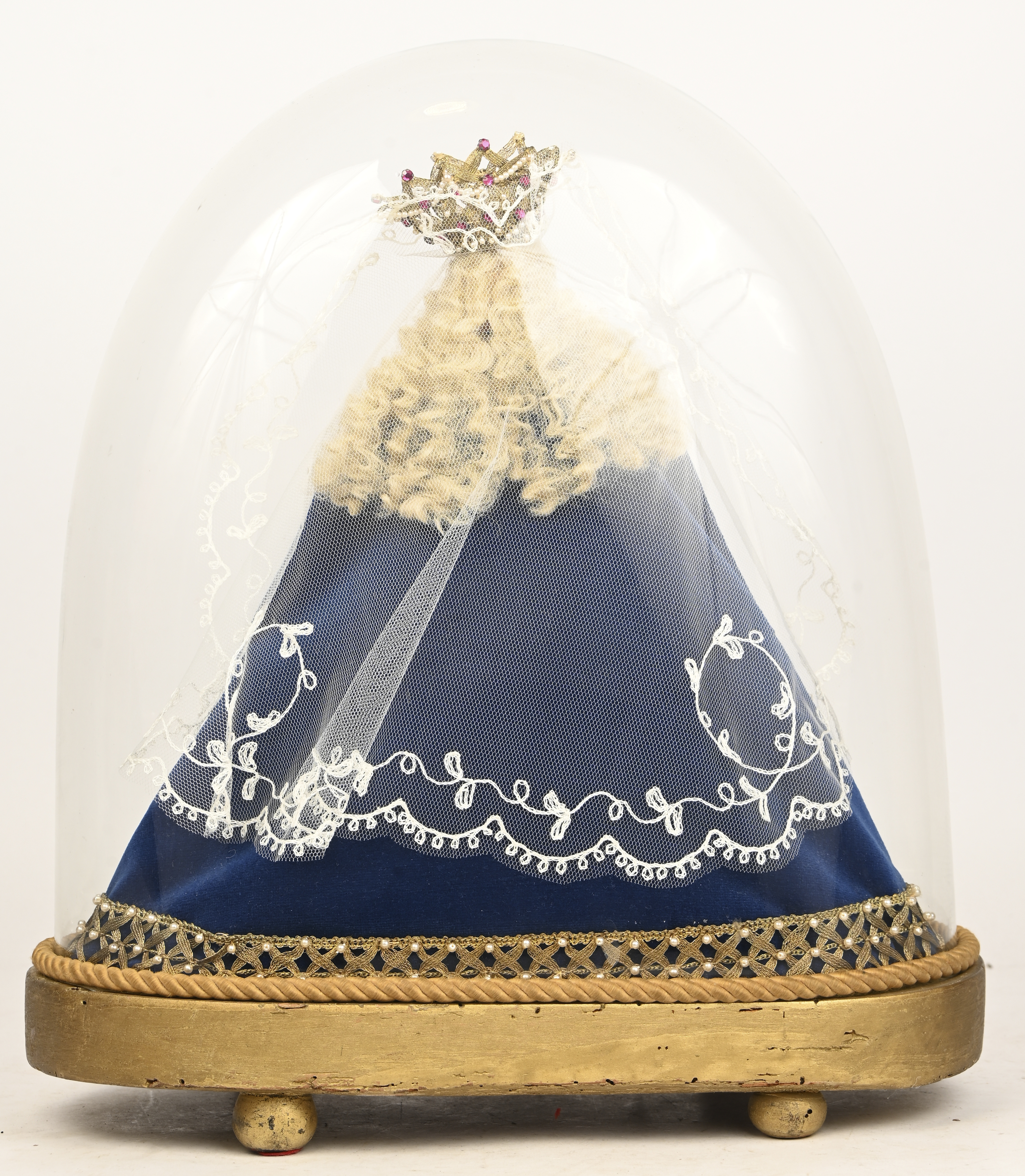 Een ovaal glazen stolp op houten sokkel met wassen Mariabeeld Een ovaal glazen stolp op houten sokkel met wassen Mariabeeld.