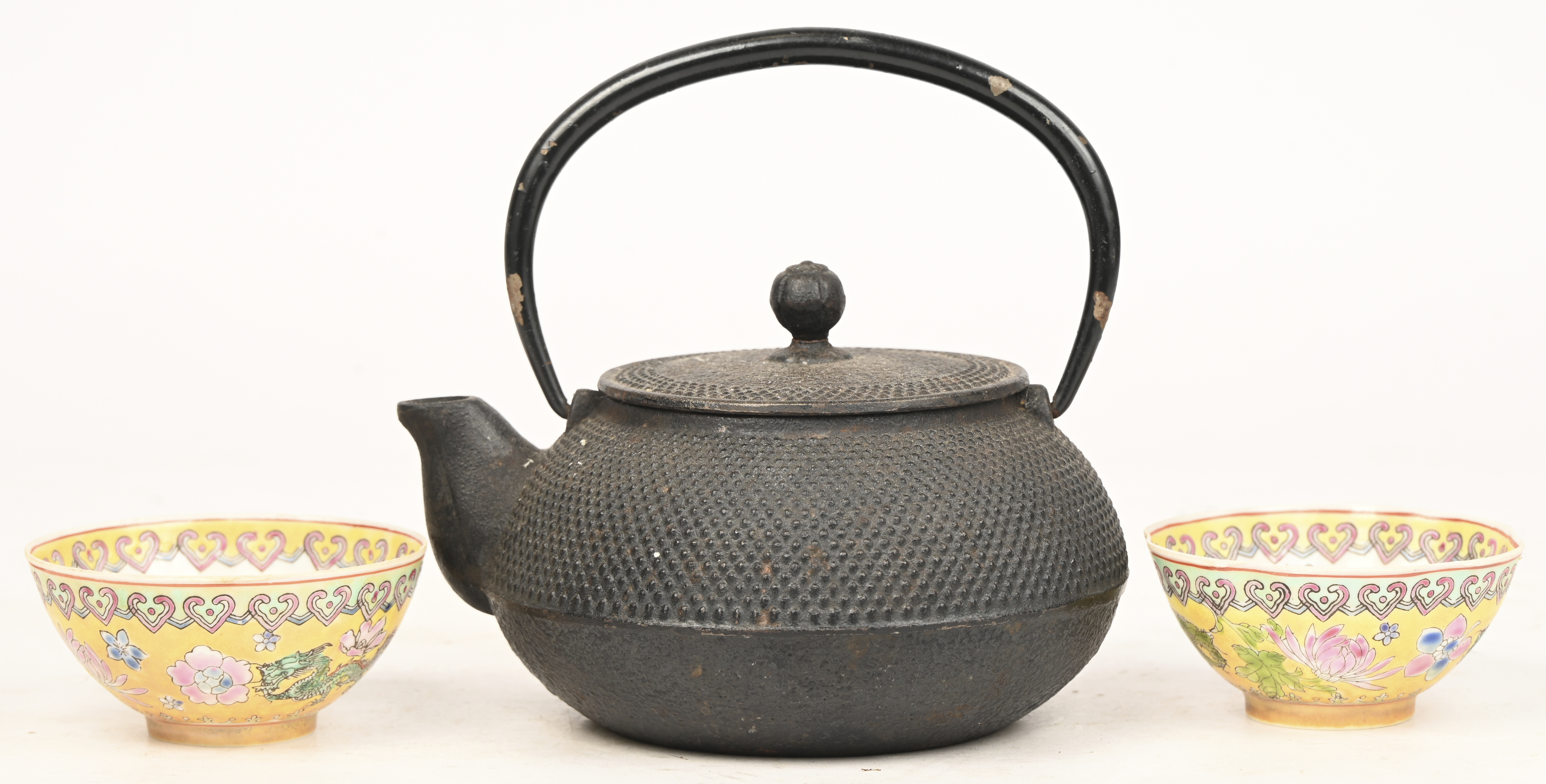 Een gietijzeren theepot en twee kommetjes van eierschaal porselein Een gietijzeren theepot en twee kommetjes van eierschaal porselein.