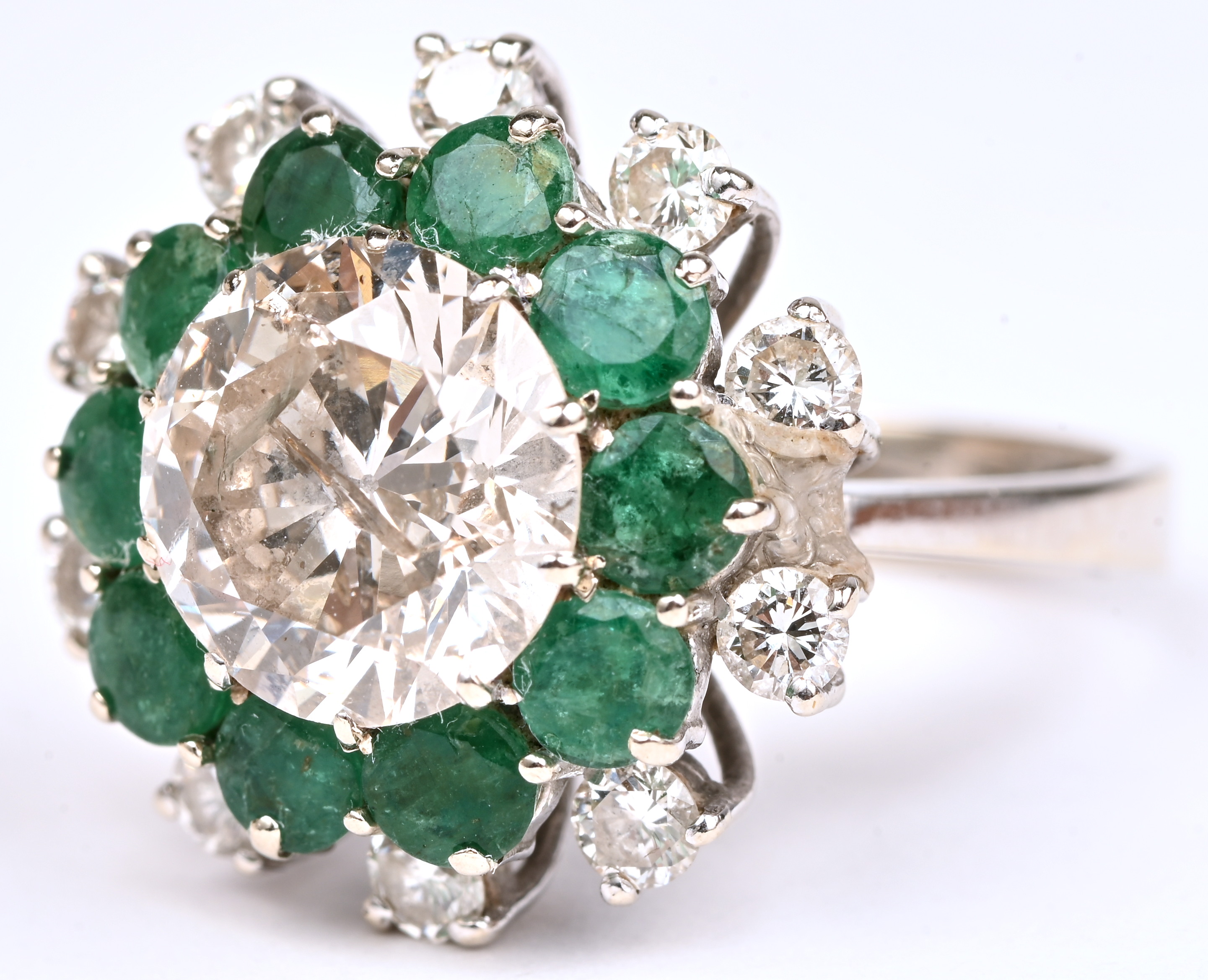 Een 18 kt witgouden ring bezet met een centrale briljant van +- 3,15 ct. en 10 briljanten met een gezamenlijk gewicht van +- 0,50 ct. en smaragden met een gezamenlijk gewicht van +- 0,86 ct Een 18 kt witgouden ring bezet met een centrale briljant van +- 3,15 ct. en 10 briljanten met een gezamenlijk gewicht van +- 0,50 ct. en smaragden met een gezamenlijk gewicht van +- 0,86 ct.