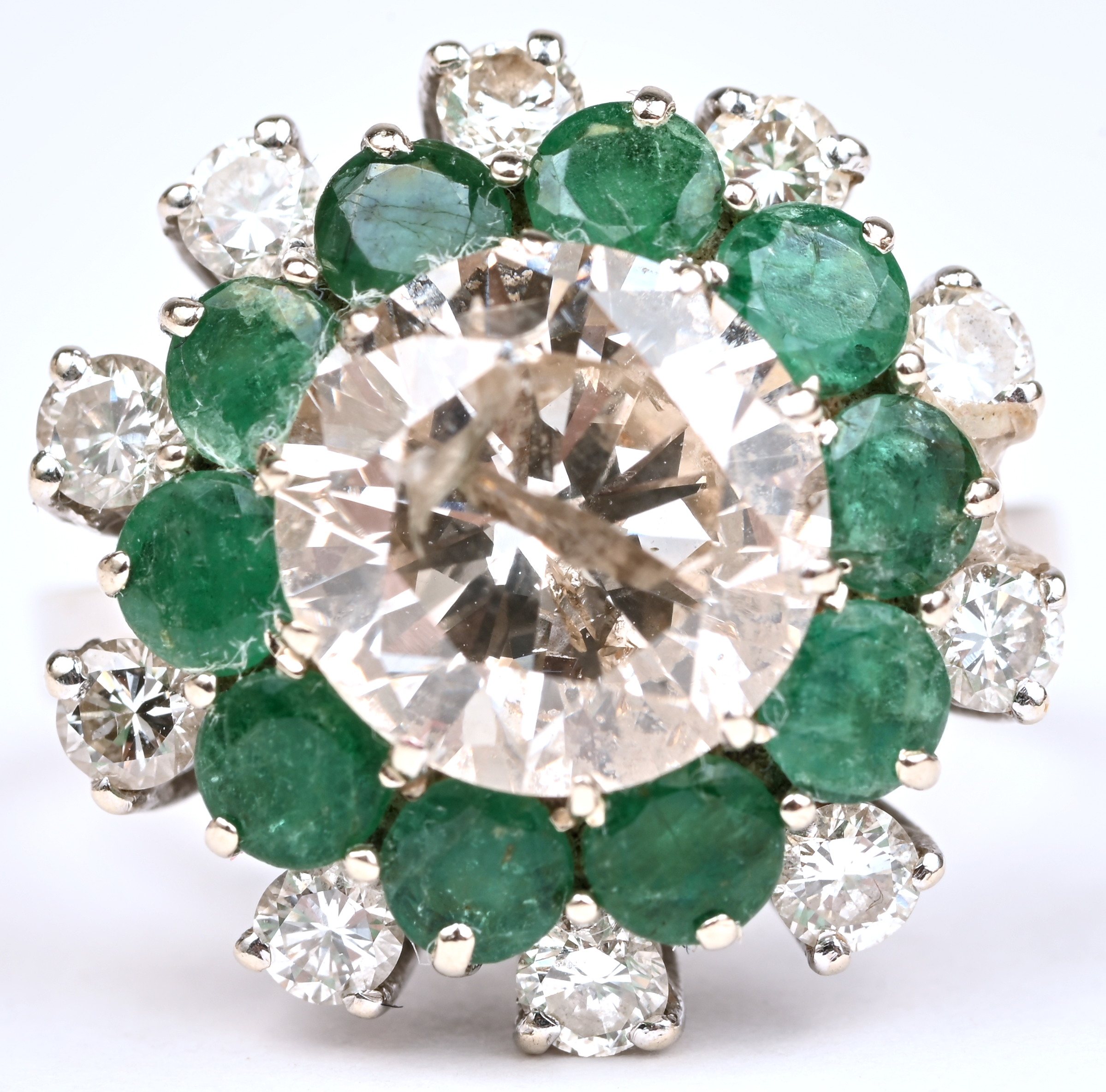 Een 18 kt witgouden ring bezet met een centrale briljant van +- 3,15 ct. en 10 briljanten met een gezamenlijk gewicht van +- 0,50 ct. en smaragden met een gezamenlijk gewicht van +- 0,86 ct Een 18 kt witgouden ring bezet met een centrale briljant van +- 3,15 ct. en 10 briljanten met een gezamenlijk gewicht van +- 0,50 ct. en smaragden met een gezamenlijk gewicht van +- 0,86 ct.