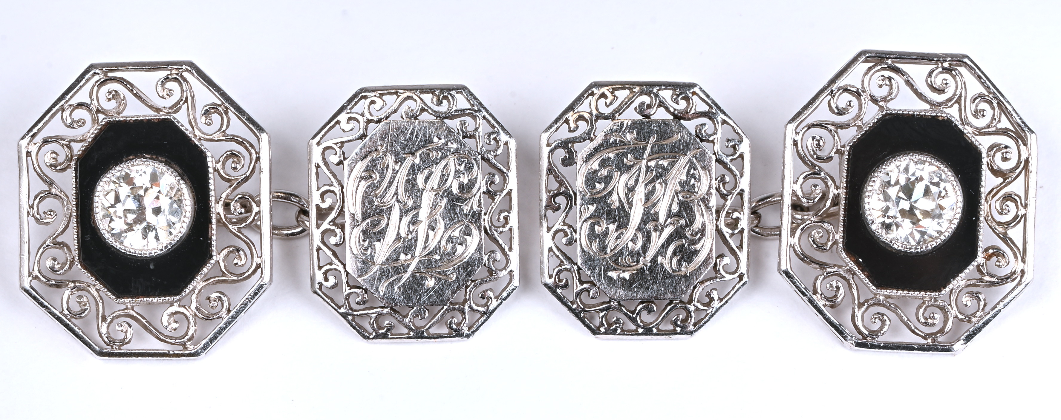 Een paar platina manchetknopen bezet met 2 briljanten met een gezamenlijk gewicht van +- 1 ct. en onyx Een paar platina manchetknopen bezet met 2 briljanten met een gezamenlijk gewicht van +- 1 ct. en onyx.
