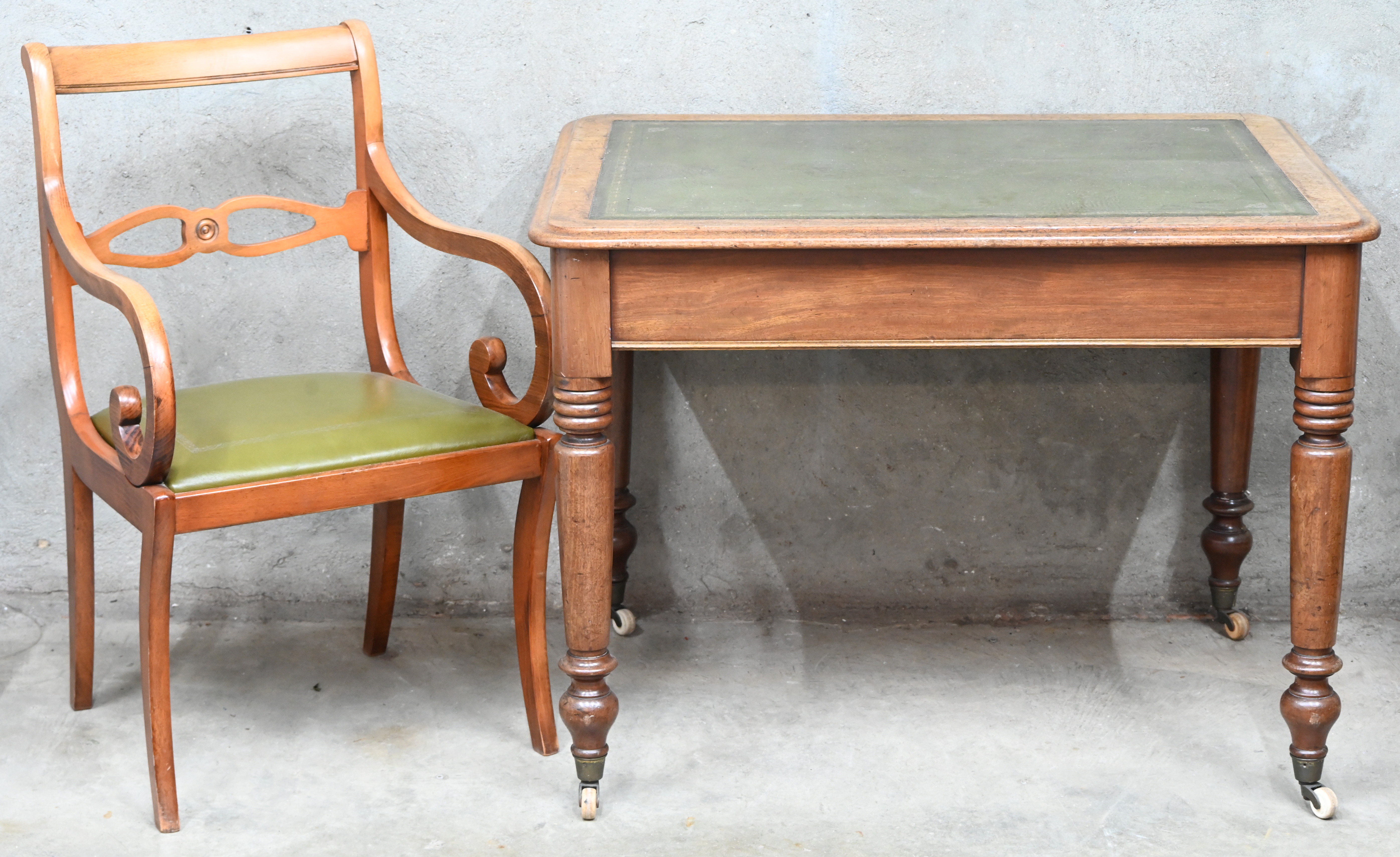 Een schrijftafel op wieltjes met groen lederen blad en twee laden. Met beukenhouten armstoel Een schrijftafel op wieltjes met groen lederen blad en twee laden. Met beukenhouten armstoel.