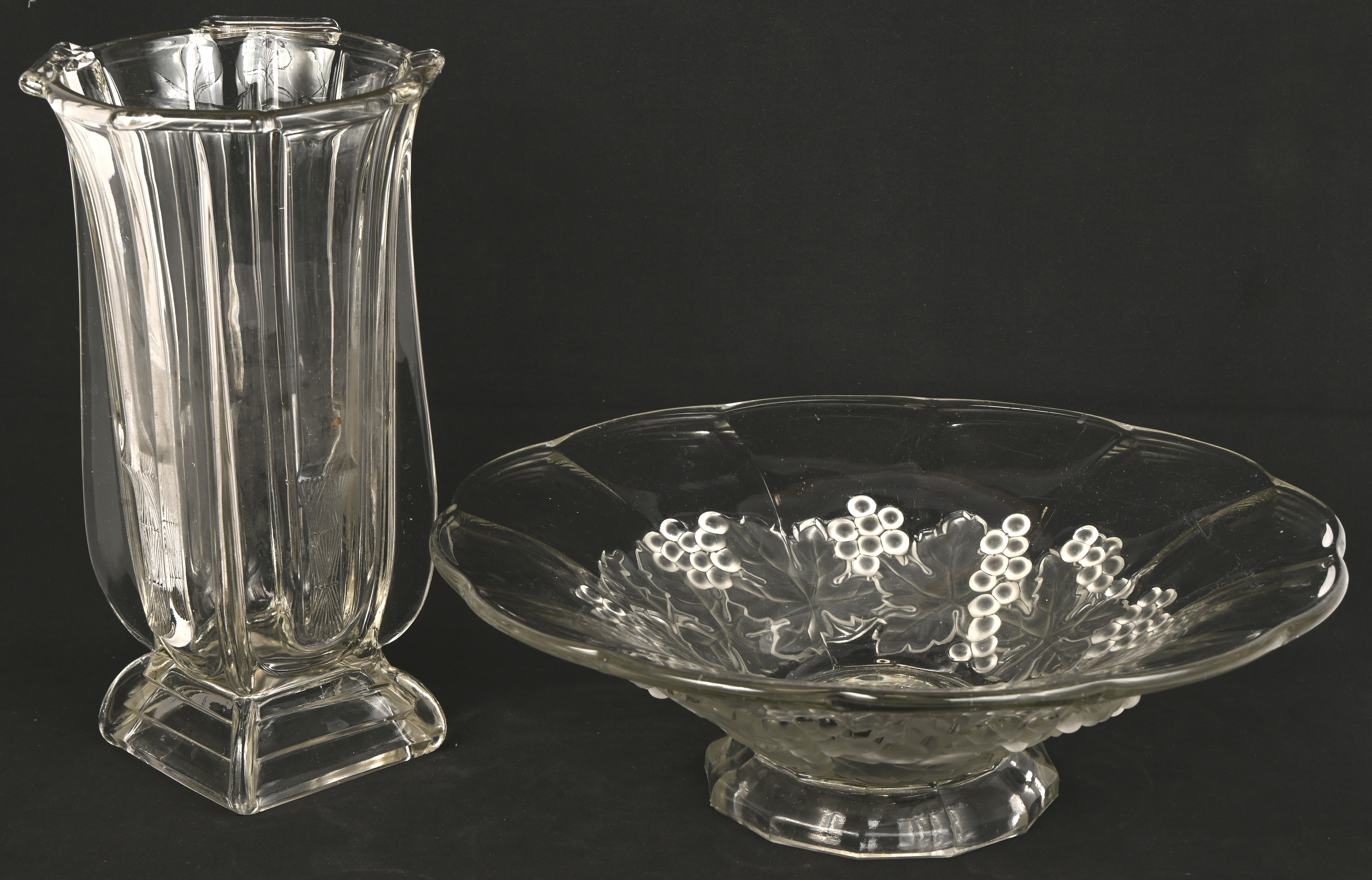 Een lot van twee gegoten kleurloos kristallen voorwerpen, een schaal met druivenranken en een art deco stijl vaas Een lot van twee gegoten kleurloos kristallen voorwerpen, een schaal met druivenranken en een art deco stijl vaas.