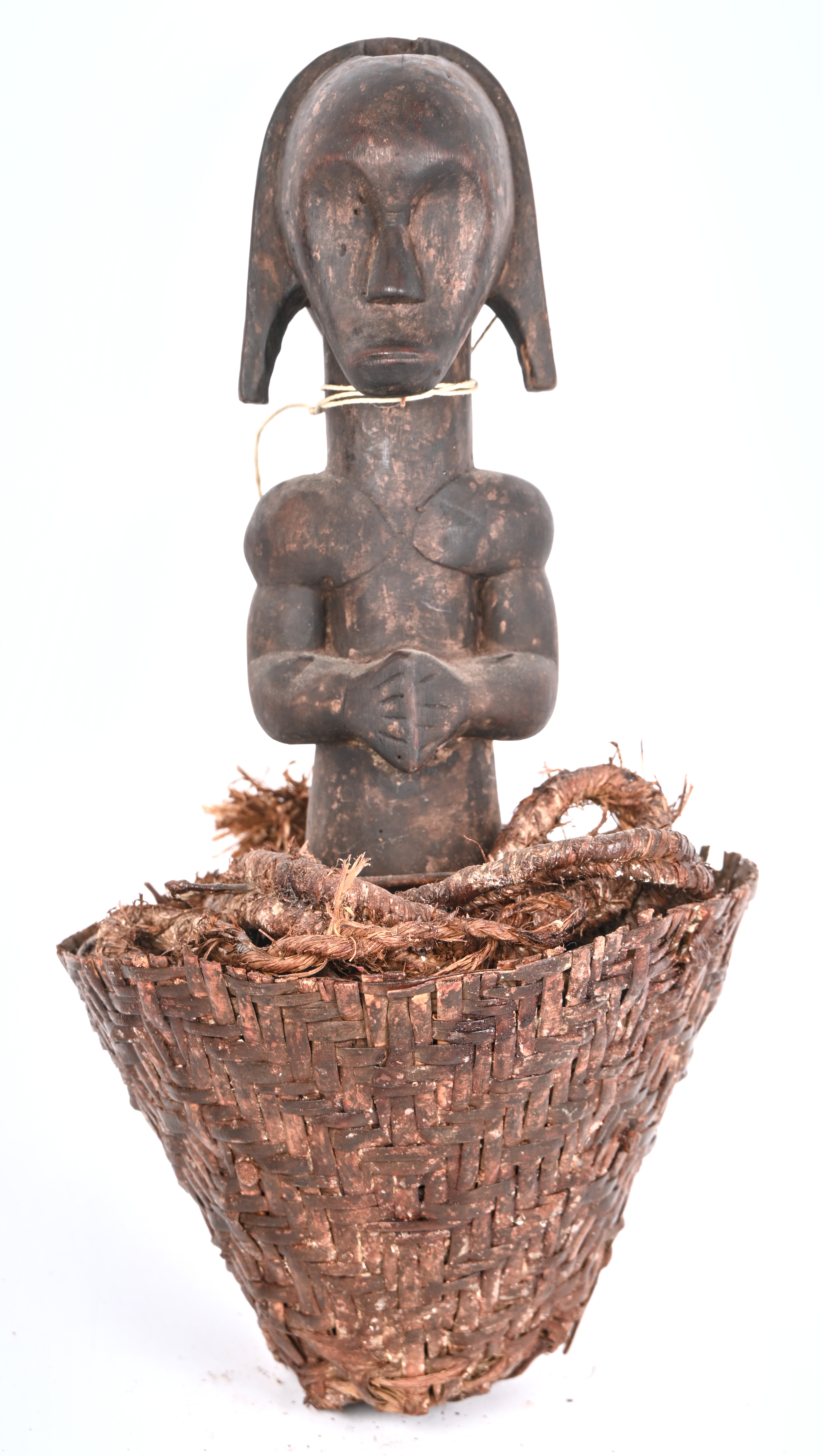 Een voorouderbeeld van gebeeldhouwd hout in een rieten mandje Een voorouderbeeld van gebeeldhouwd hout in een rieten mandje.
