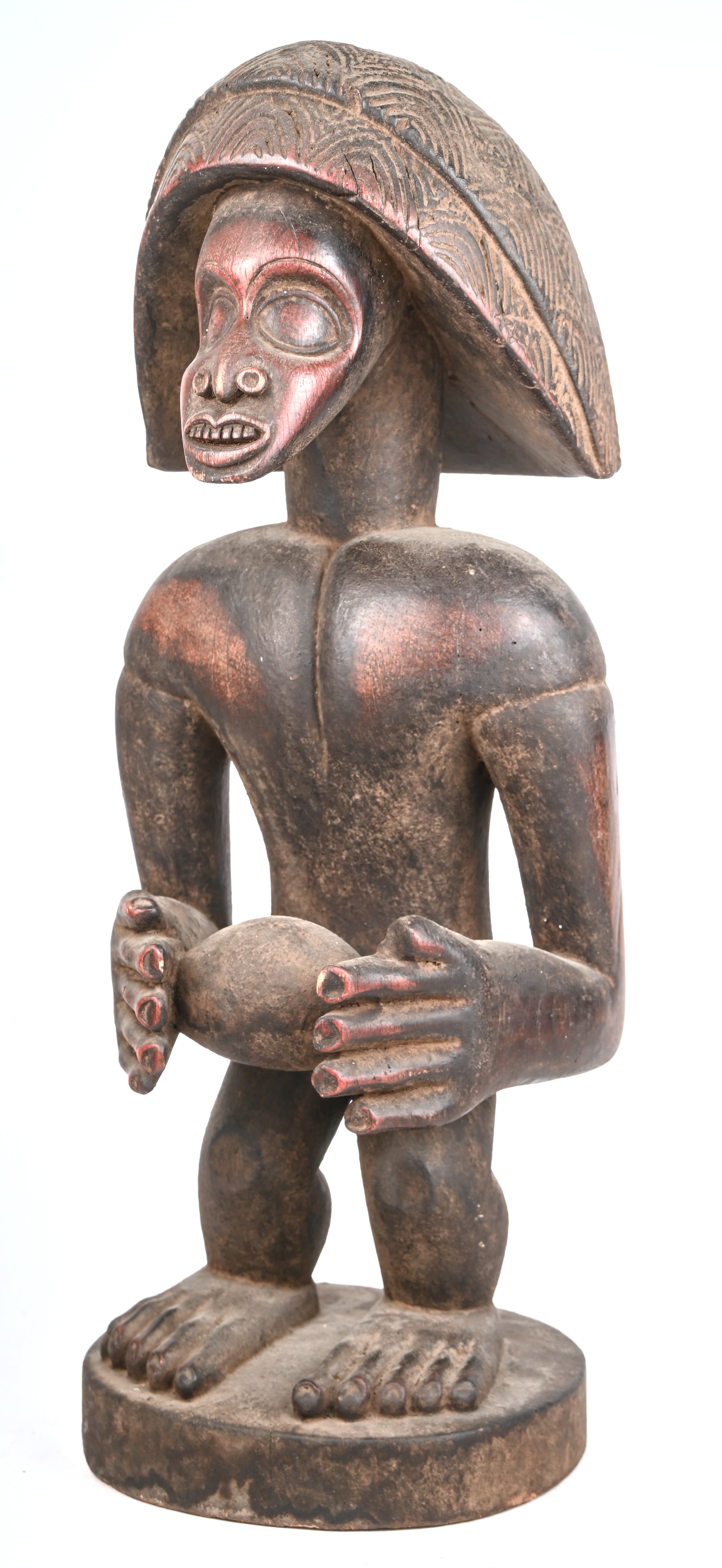 Houten beeld van een staande figuur ruime hoofdtooi en met een eirond voorwerp in de handen Houten beeld van een staande figuur ruime hoofdtooi en met een eirond voorwerp in de handen.