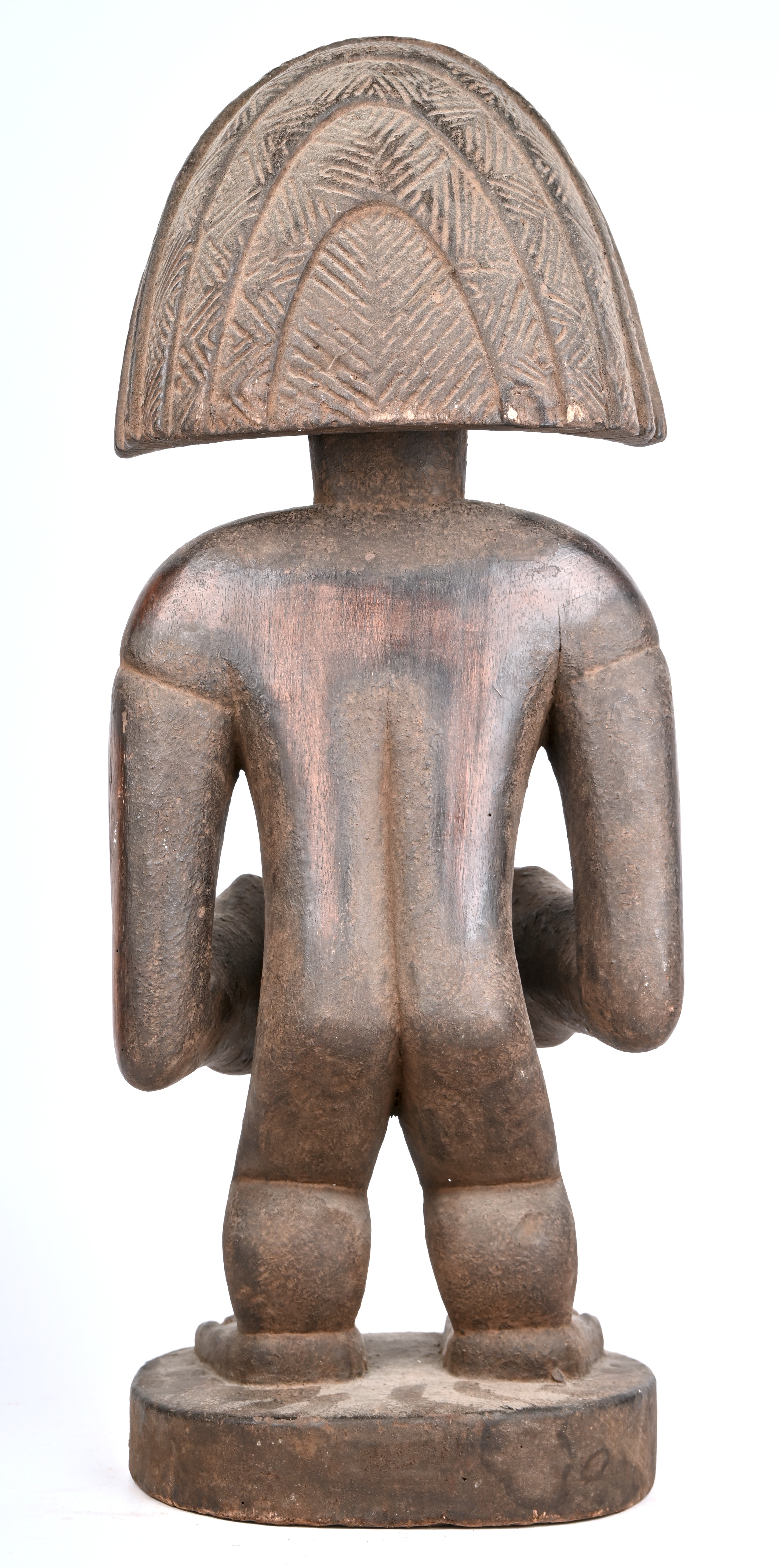 Houten beeld van een staande figuur ruime hoofdtooi en met een eirond voorwerp in de handen Houten beeld van een staande figuur ruime hoofdtooi en met een eirond voorwerp in de handen.