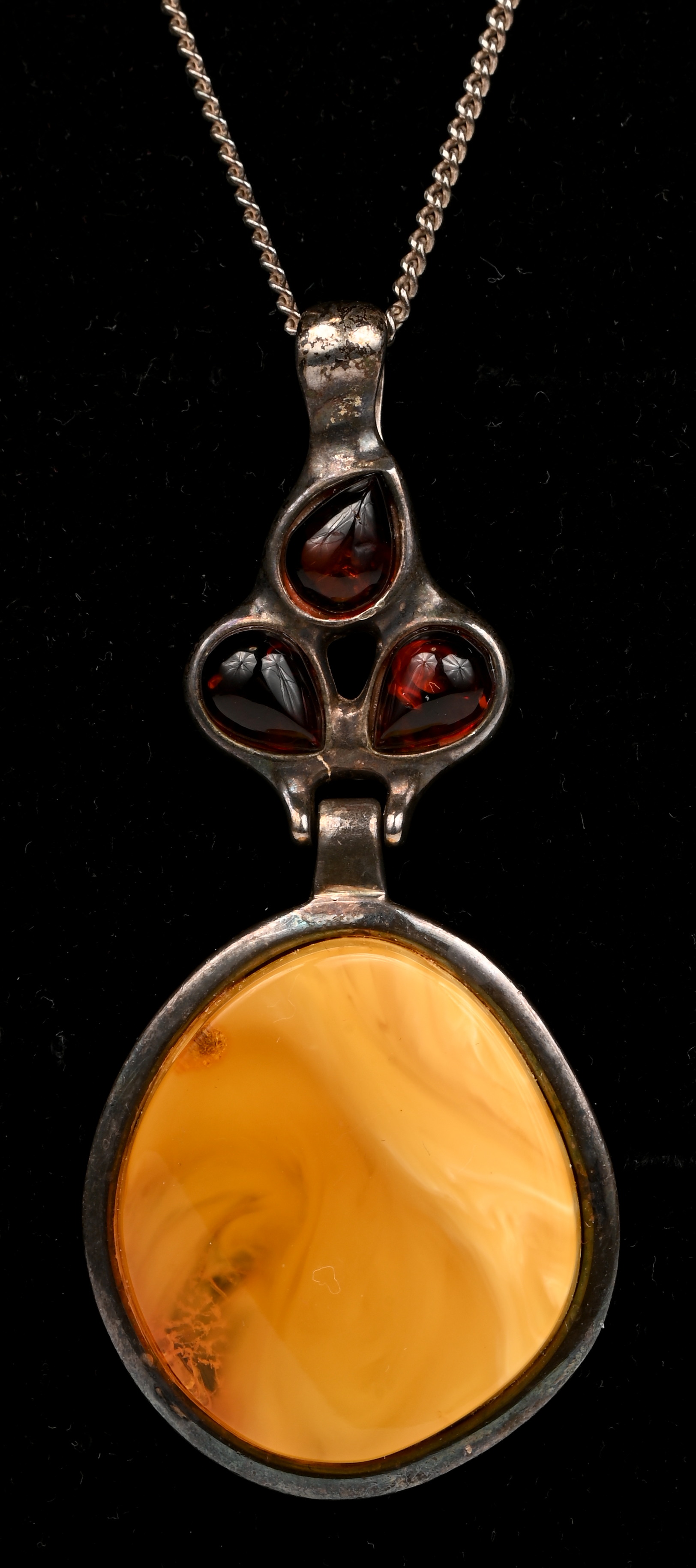 Een zilveren ketting met hanger bezet met amber en barnsteen. 935‰ Een zilveren ketting met hanger bezet met amber en barnsteen. 935‰.