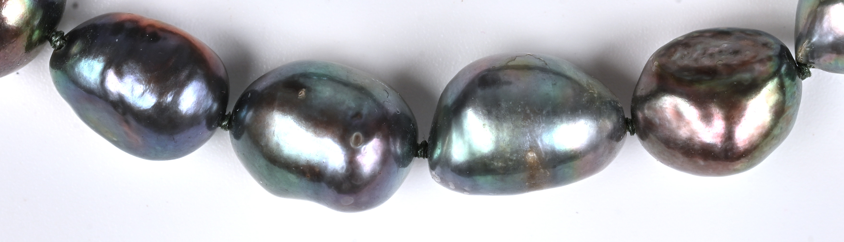 Een halssnoer met bijpassende armband bezet met verschillende donker grijze barokparels en met verguld slot Een halssnoer met bijpassende armband bezet met verschillende donker grijze barokparels en met verguld slot.