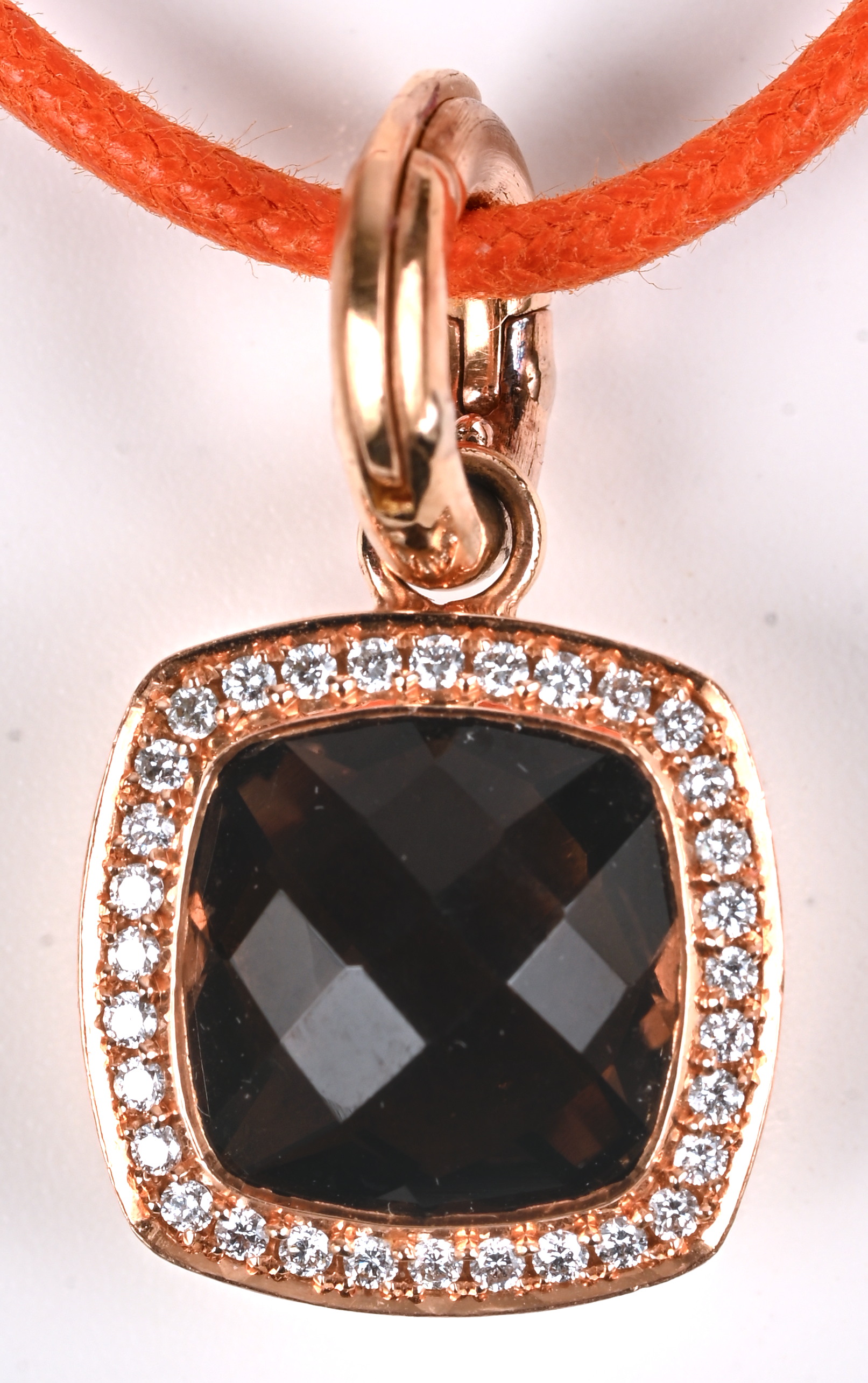Een oranje koortketting met hanger van 18 kt roze goud bezet met diamanten met een gezamenlijk gewicht van +- 0,20 ct. en een gefaceteerde granaat Een oranje koortketting met hanger van 18 kt roze goud bezet met diamanten met een gezamenlijk gewicht van +- 0,20 ct. en een gefaceteerde granaat.