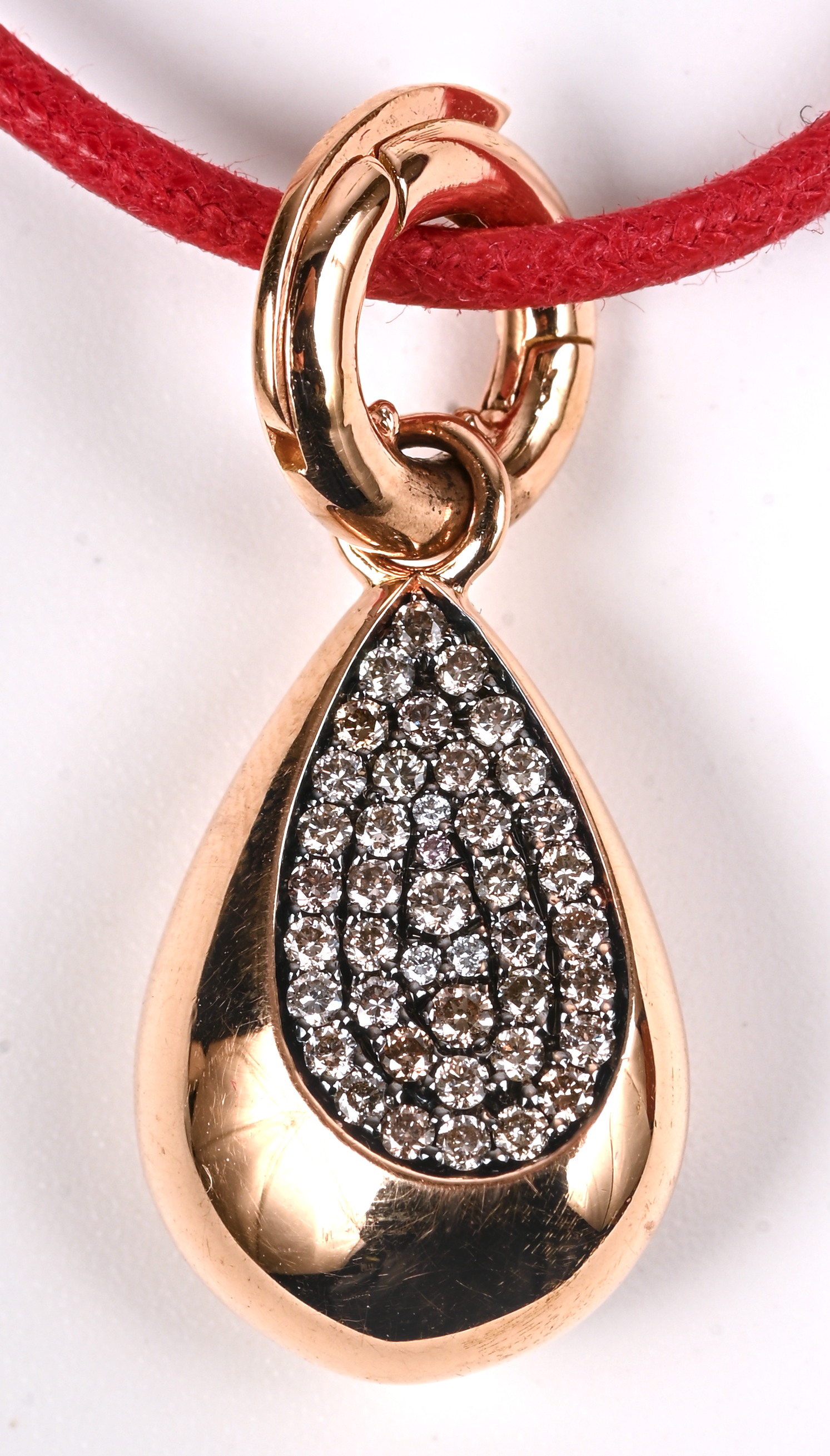 Een rode koortketting met hanger van 18 kt roze goud bezet met diamanten met een gezamenlijk gewicht van +- 0,22 ct Een rode koortketting met hanger van 18 kt roze goud bezet met diamanten met een gezamenlijk gewicht van +- 0,22 ct.