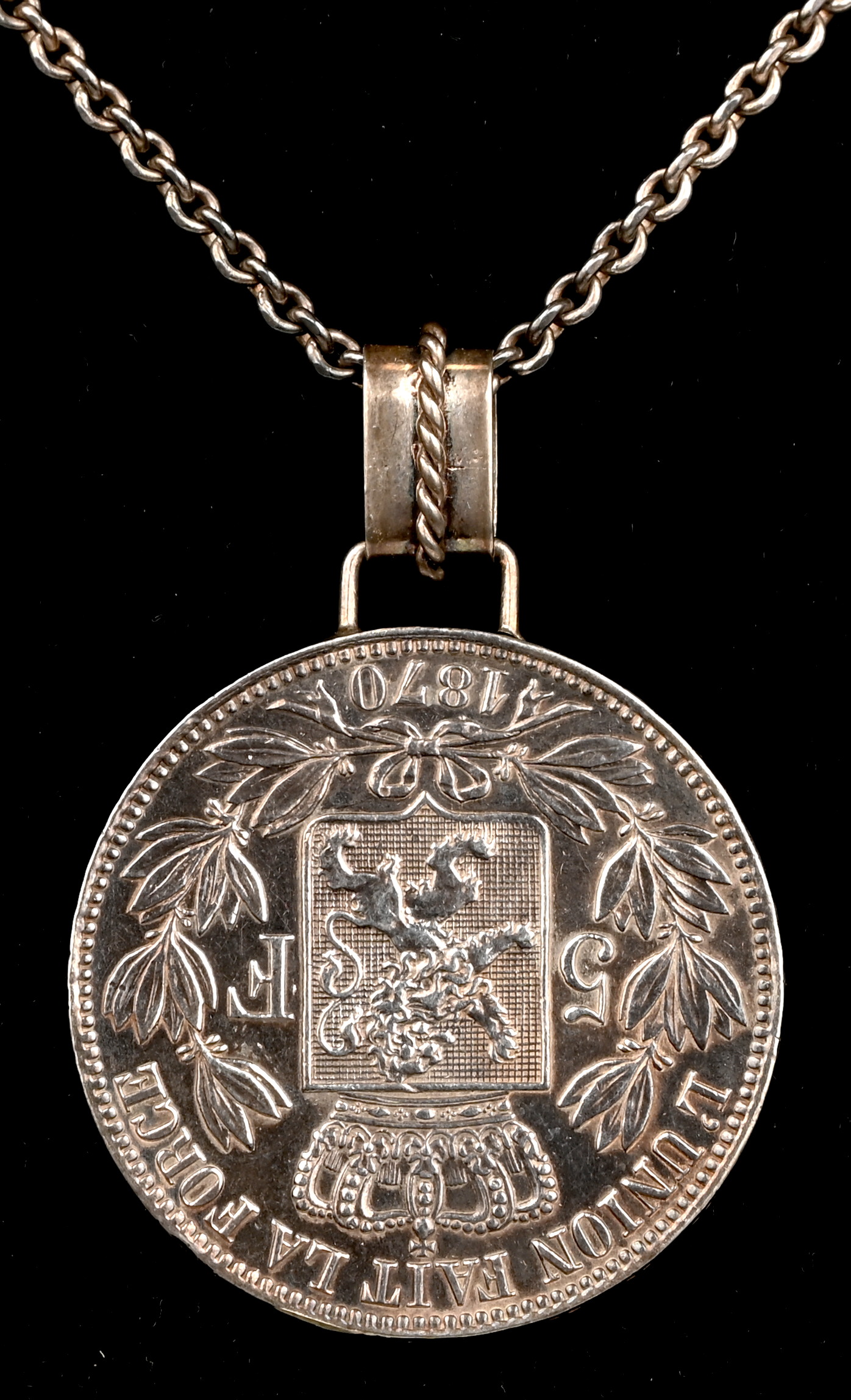 Een ketting met een hanger van zilver met een 5 Franc munt van Leopold II en wapenschild. 1870 Een ketting met een hanger van zilver met een 5 Franc munt van Leopold II en wapenschild. 1870.