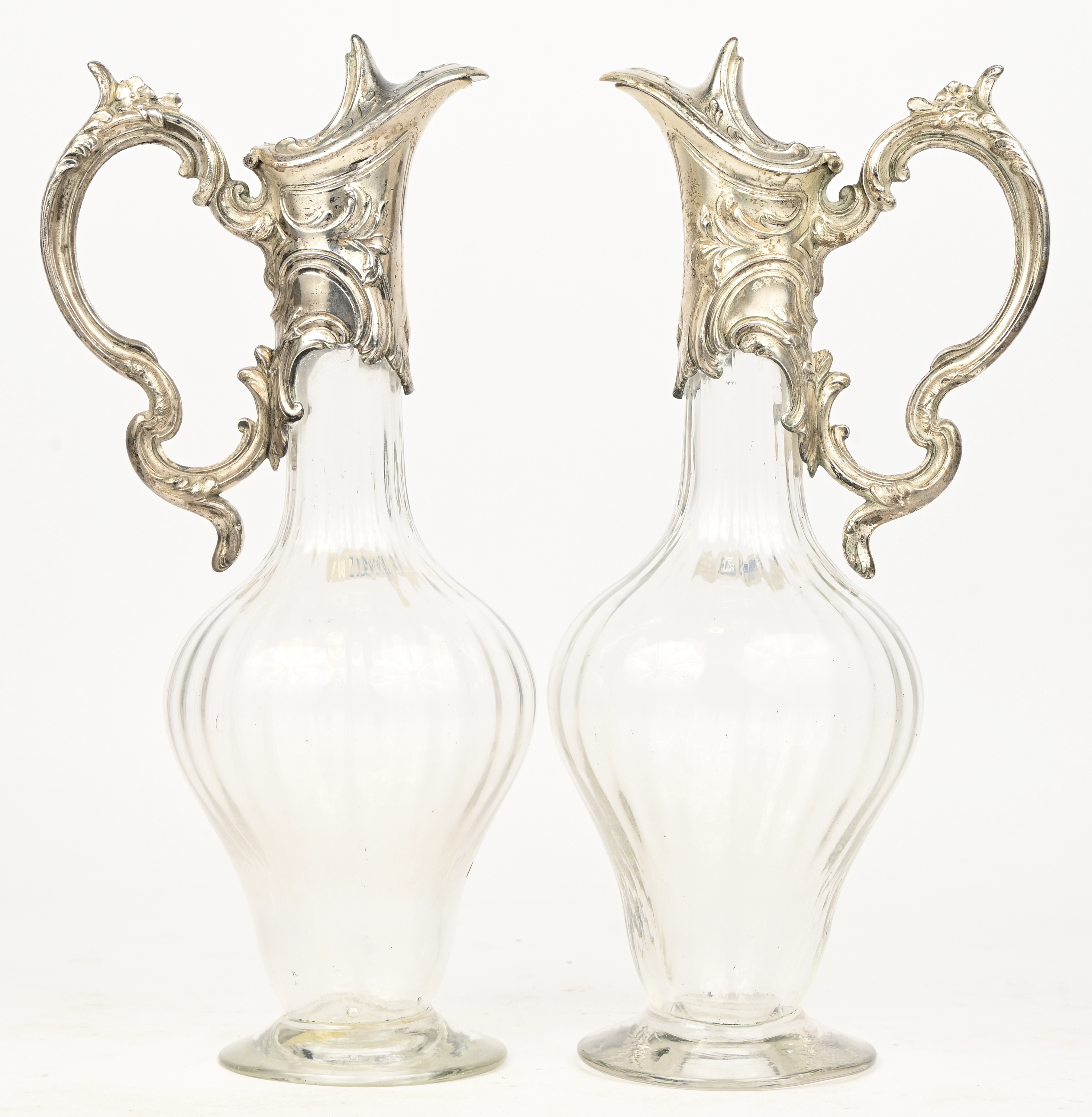 Een set van 2 glazen karaffen met verzilverd metalen handvat/schenkdeel Een set van 2 glazen karaffen met verzilverd metalen handvat/schenkdeel.