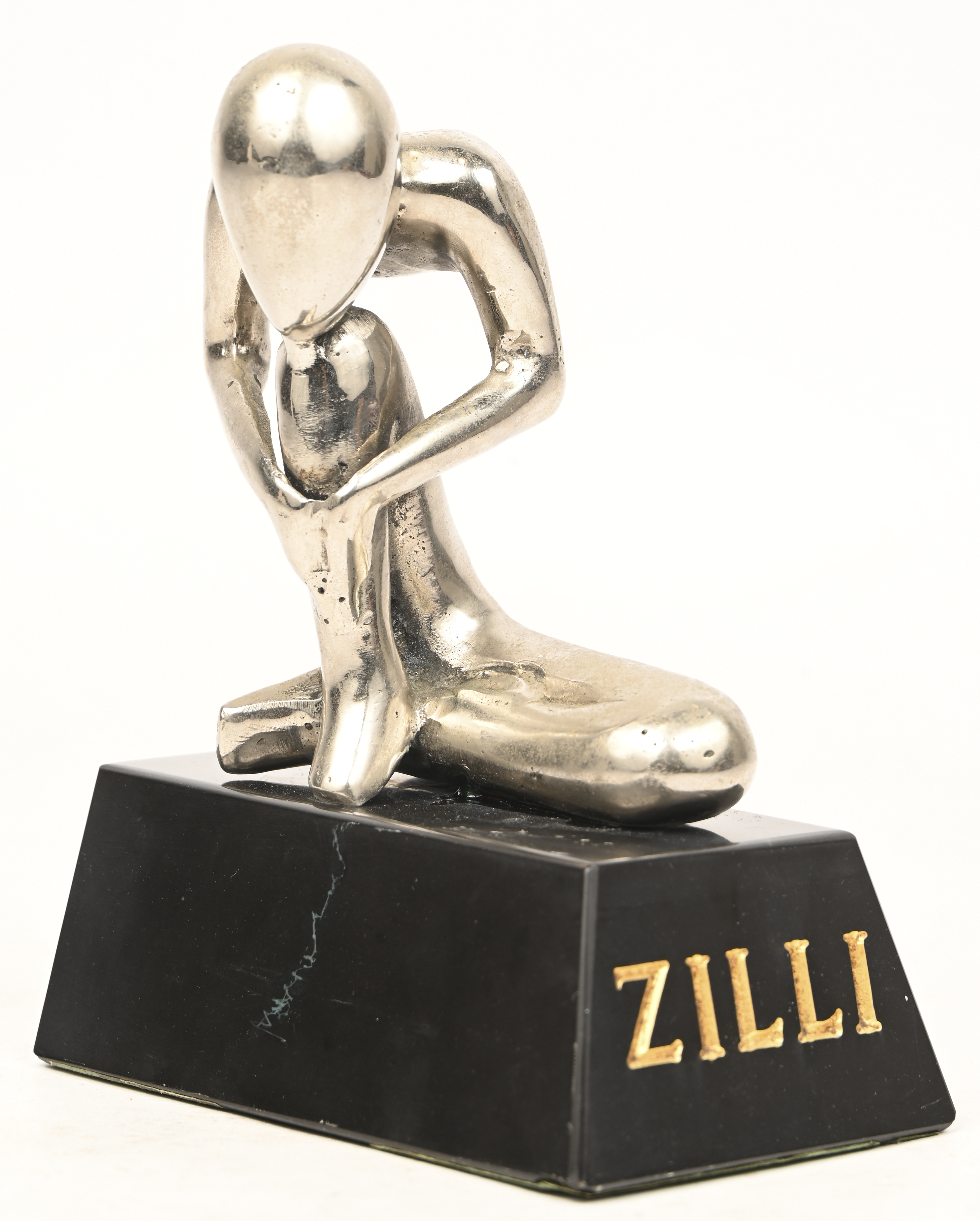 Een modern metalen beeld op marmeren sokkel met opschrift Zilli Een modern metalen beeld op marmeren sokkel met opschrift Zilli.