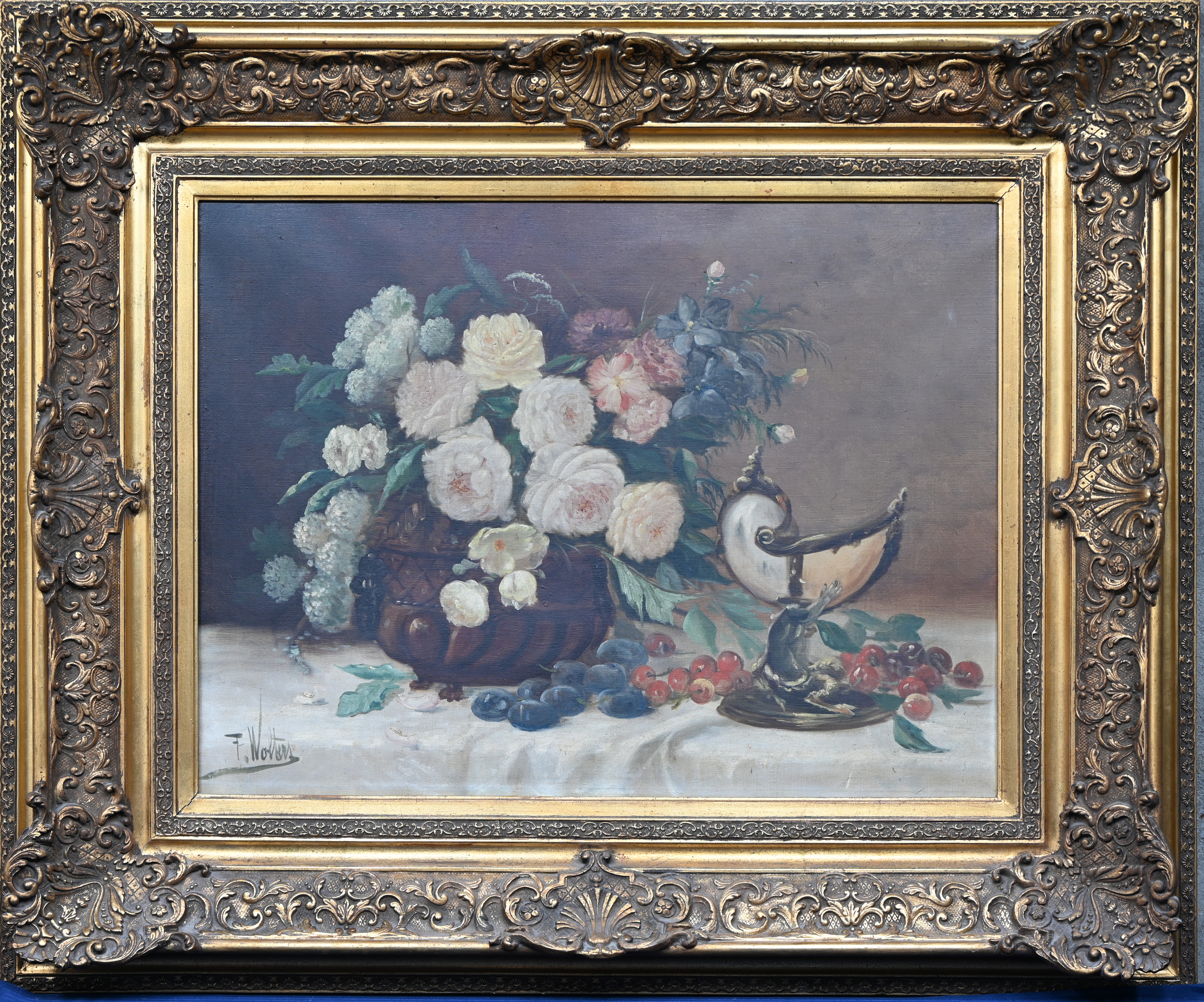 ‘Stilleven met bloemen en fruit’, olieverf op doek. Naar de 19e eeuw, getekend F. Wolters. In rijkelijk versierde goudkleurige kader ‘Stilleven met bloemen en fruit’, olieverf op doek. Naar de 19e eeuw, getekend F. Wolters. In rijkelijk versierde goudkleurige kader.