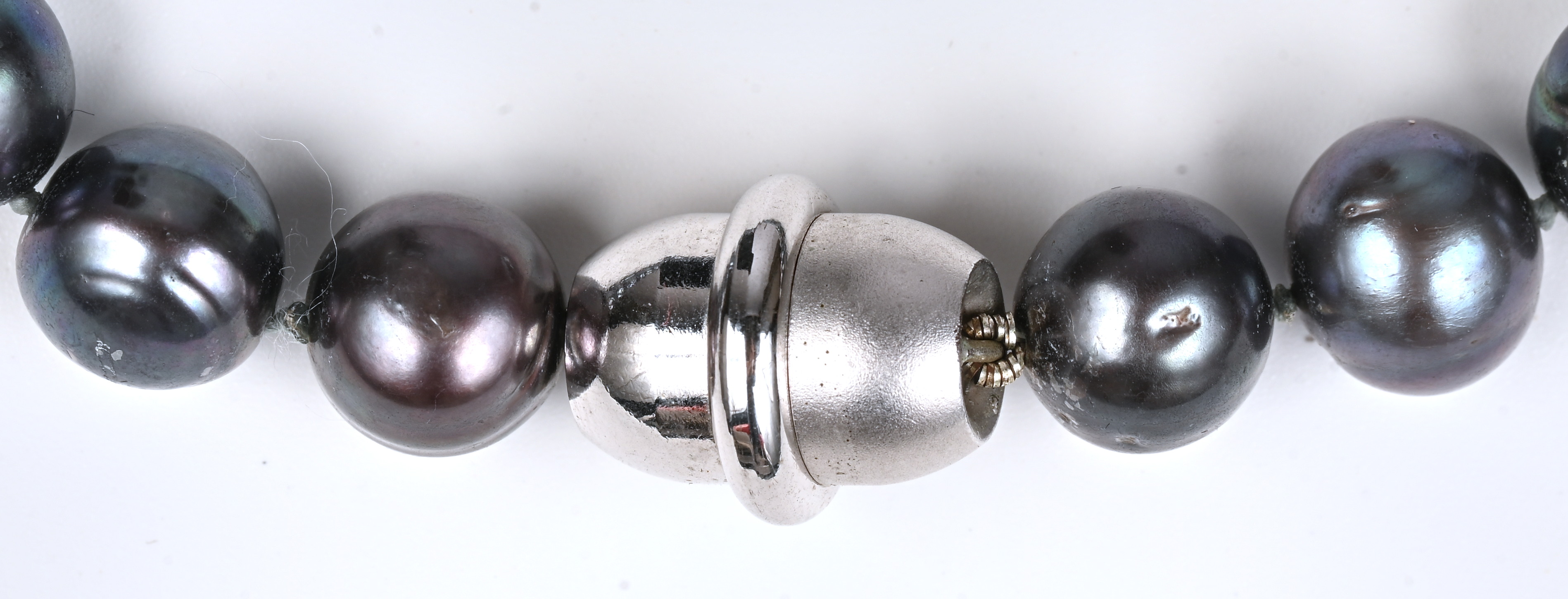 Een halssnoer van grijze parels bezet met magneetslot Een halssnoer van grijze parels bezet met magneetslot.
