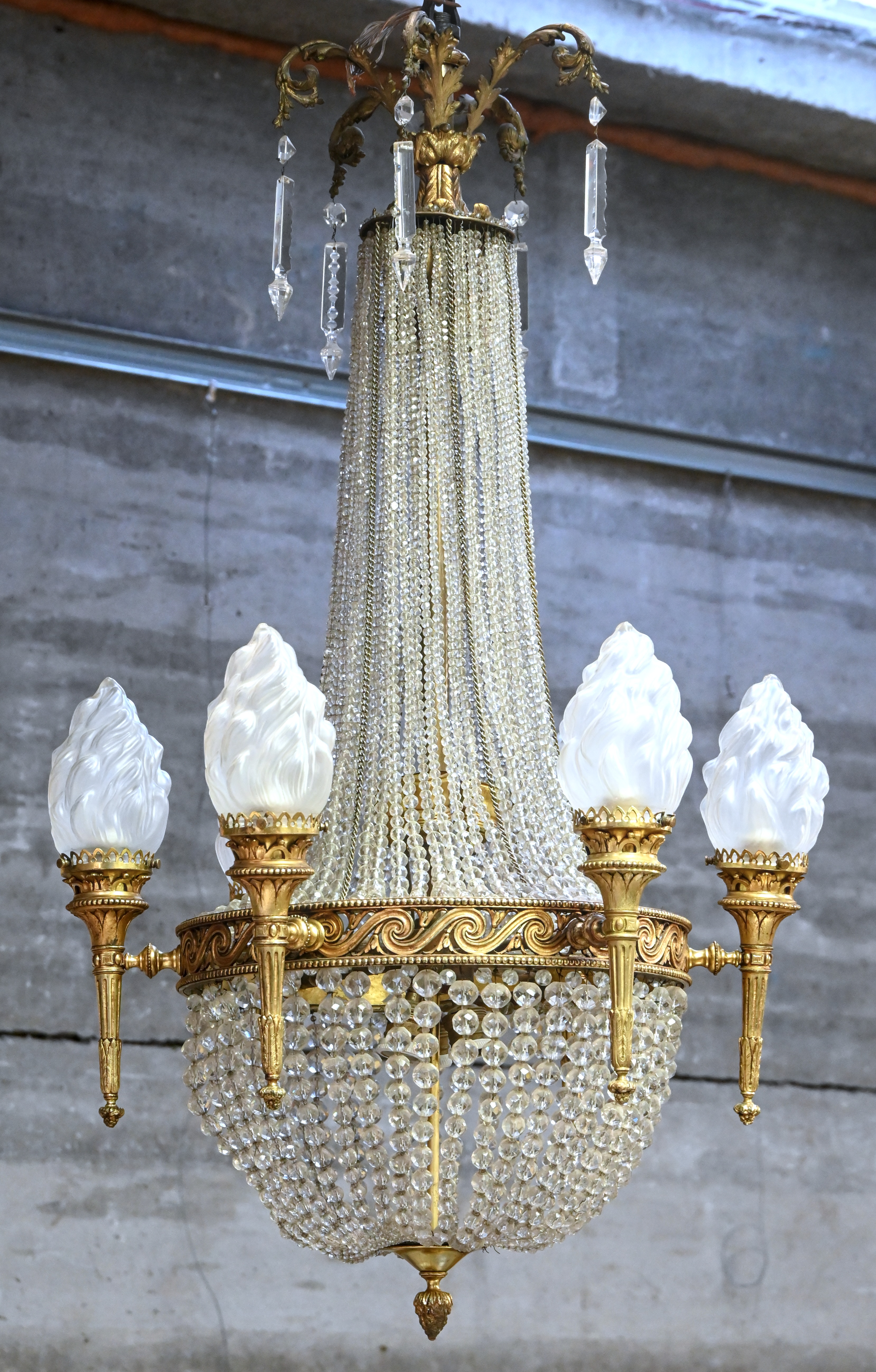 Een verguld messingen sac à perles-luchter in Empire-stijl, zes lichtpunten met vlamvormige gesatineerde glazen kapjes Een verguld messingen sac à perles-luchter in Empire-stijl, zes lichtpunten met vlamvormige gesatineerde glazen kapjes.