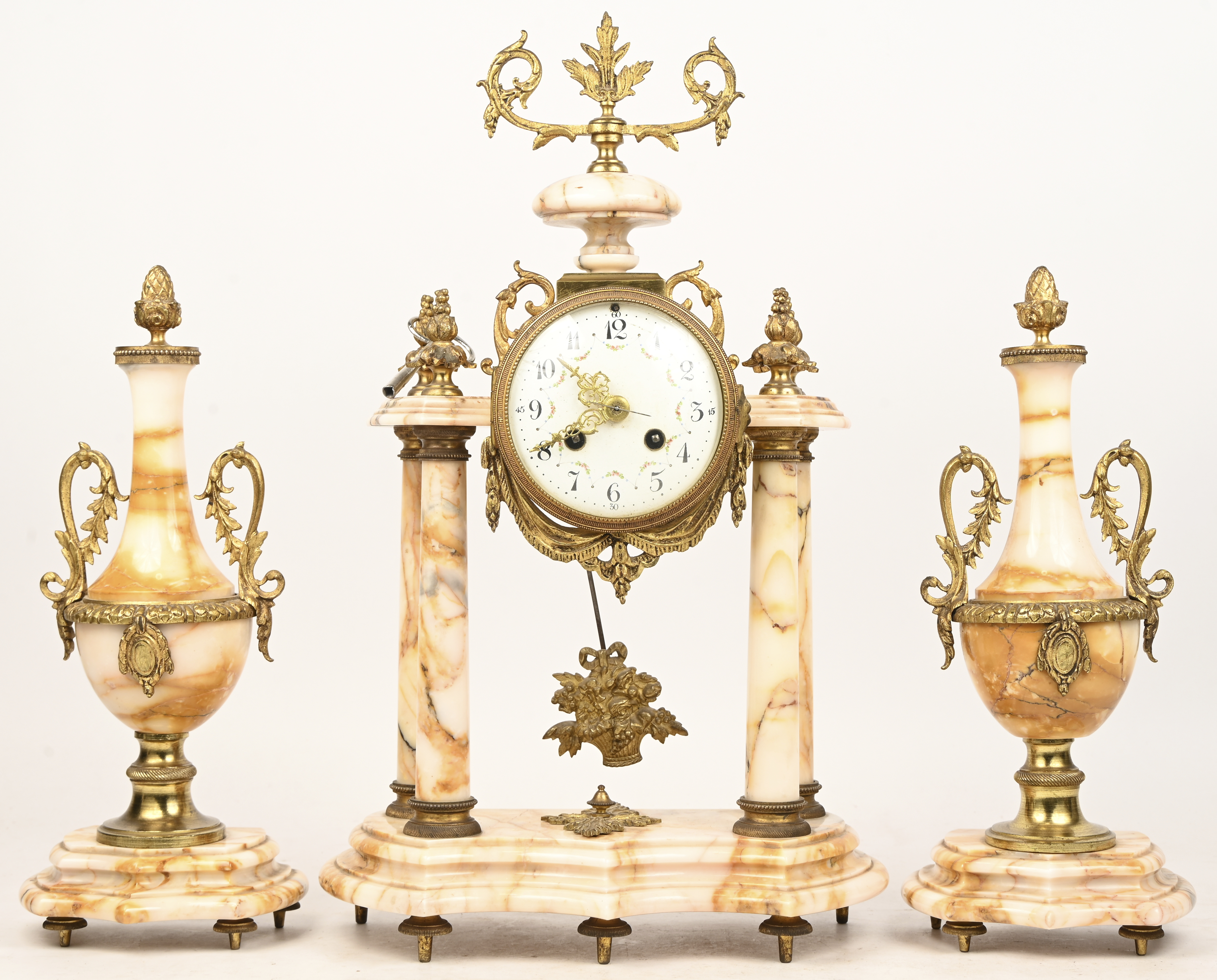 Een Franse marmeren schouwpendule met 2 bijhorende casolettes, restauratie boven de linker zuil Een Franse marmeren schouwpendule met 2 bijhorende casolettes, restauratie boven de linker zuil.