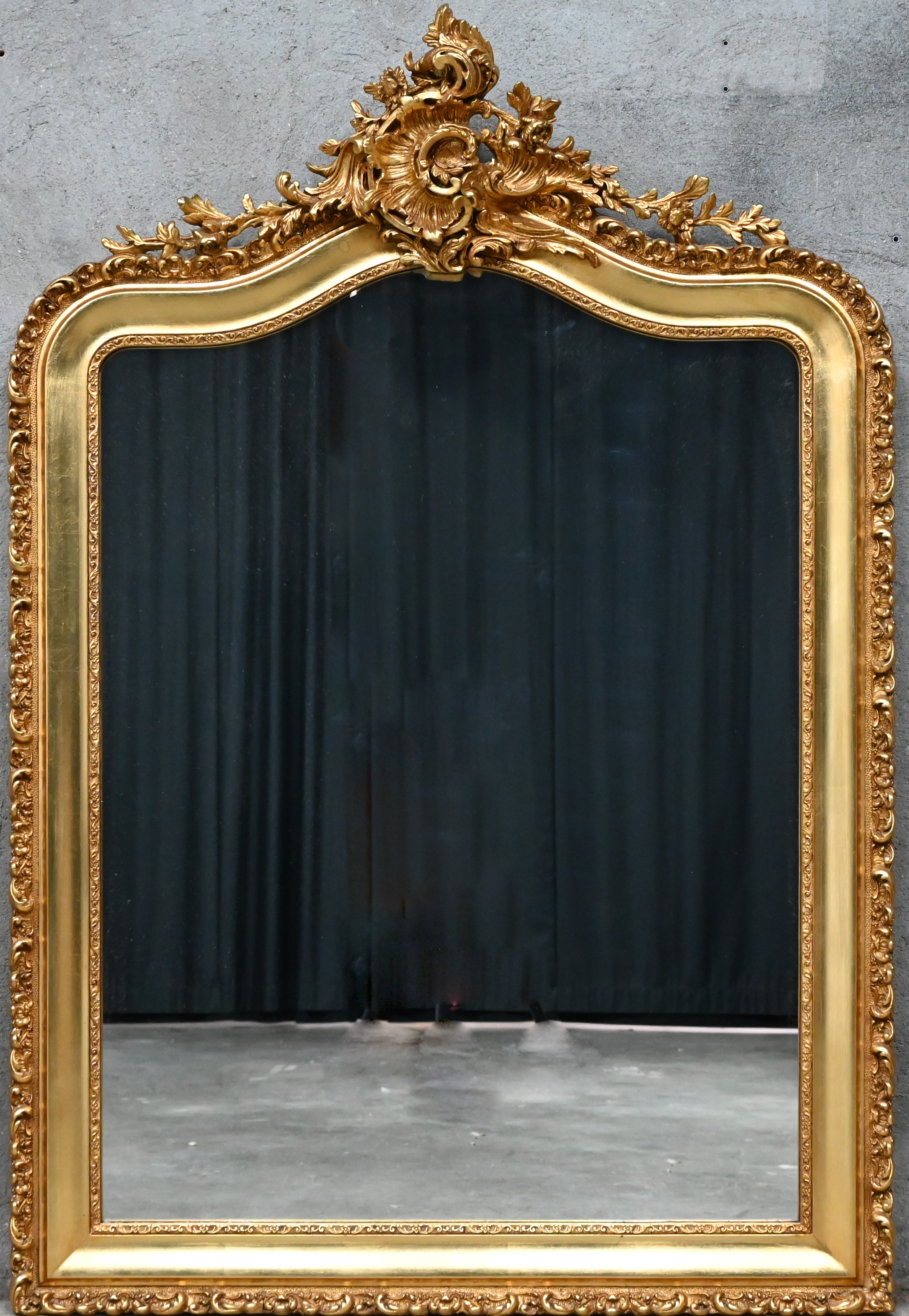 Een grote spiegel in vergulde kader en kuif in Rococo stijl Een grote spiegel in vergulde kader en kuif in Rococo stijl.