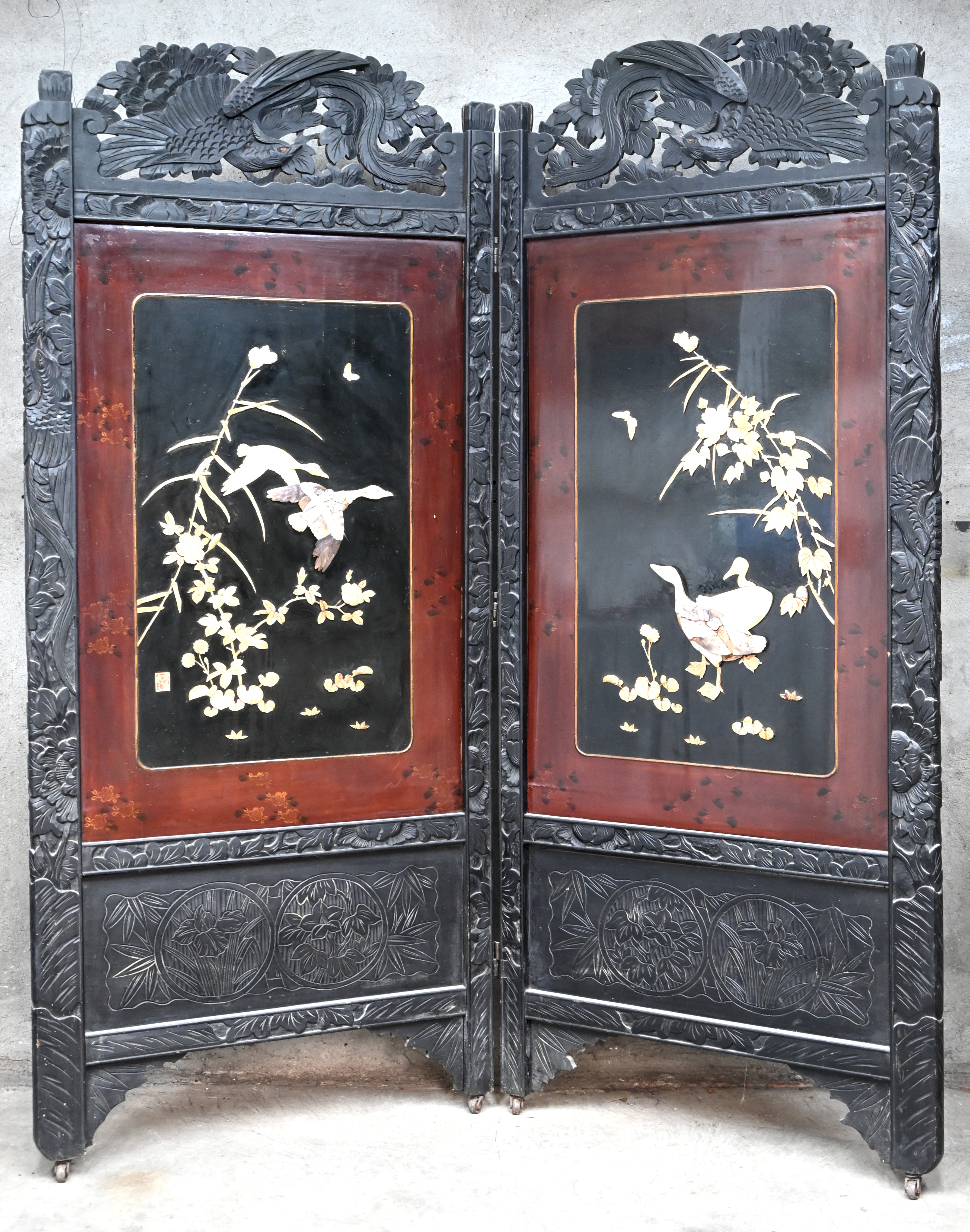 Een Aziatisch kamerscherm in twee delen. Van gesculpteerd hout, met planten en ganzen in hoogrelief. Meerdere kleine beschadigingen aan het reliëf Een Aziatisch kamerscherm in twee delen. Van gesculpteerd hout, met planten en ganzen in hoogrelief. Meerdere kleine beschadigingen aan het reliëf.