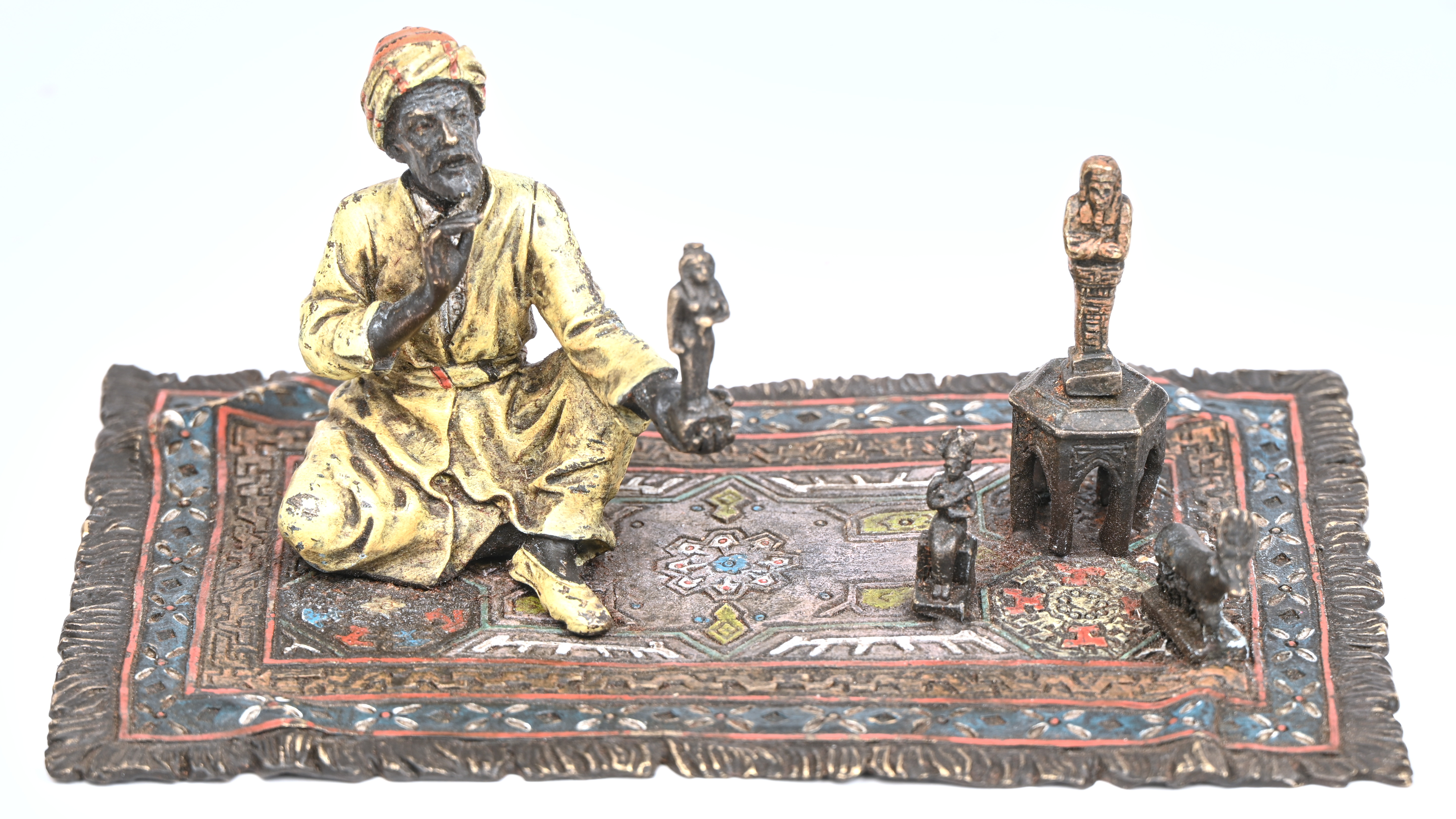 Een bronzen Arabische handelaar op een tapijt gezeten Een bronzen Arabische handelaar op een tapijt gezeten.
