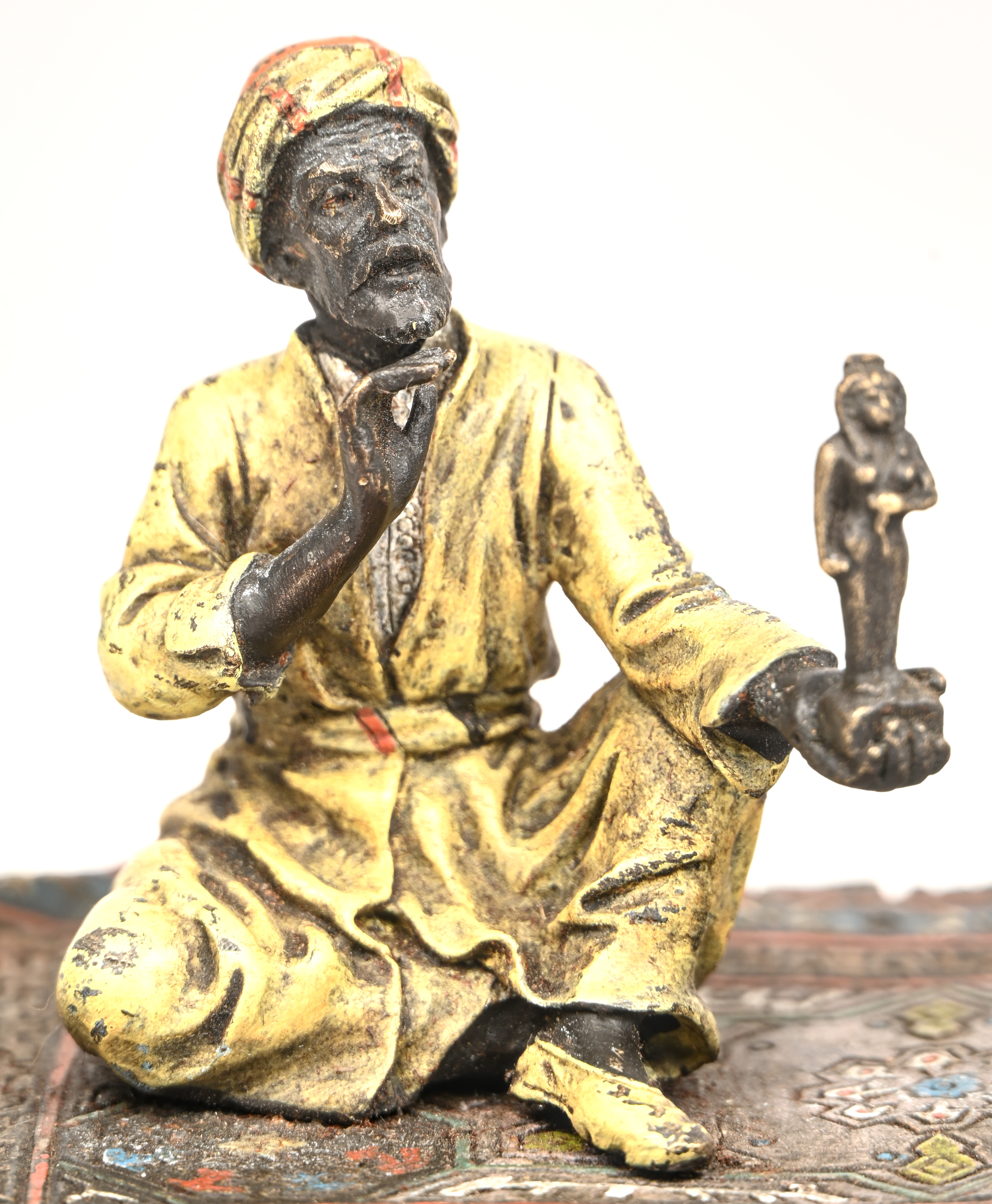 Een bronzen Arabische handelaar op een tapijt gezeten Een bronzen Arabische handelaar op een tapijt gezeten.