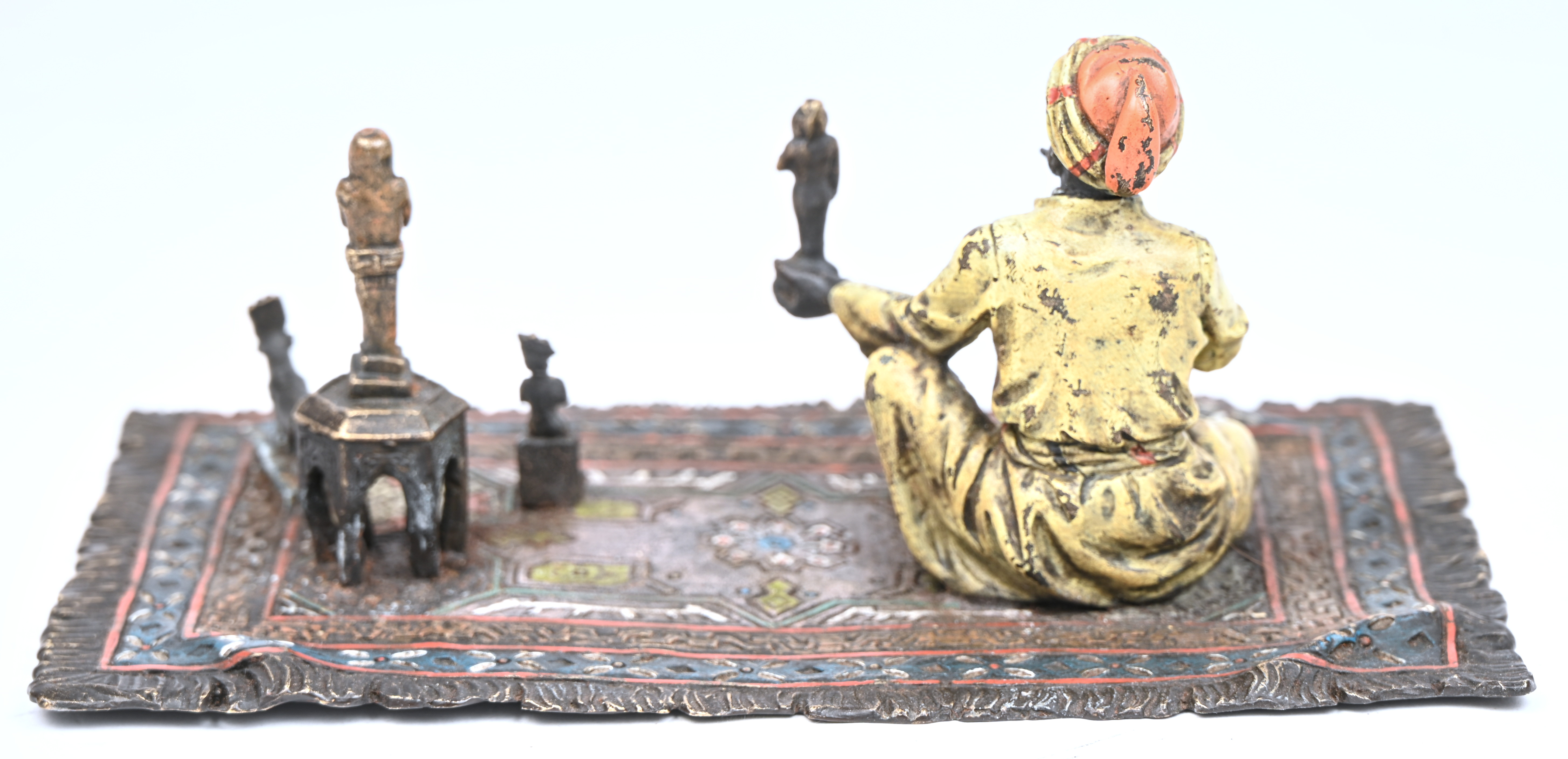 Een bronzen Arabische handelaar op een tapijt gezeten Een bronzen Arabische handelaar op een tapijt gezeten.