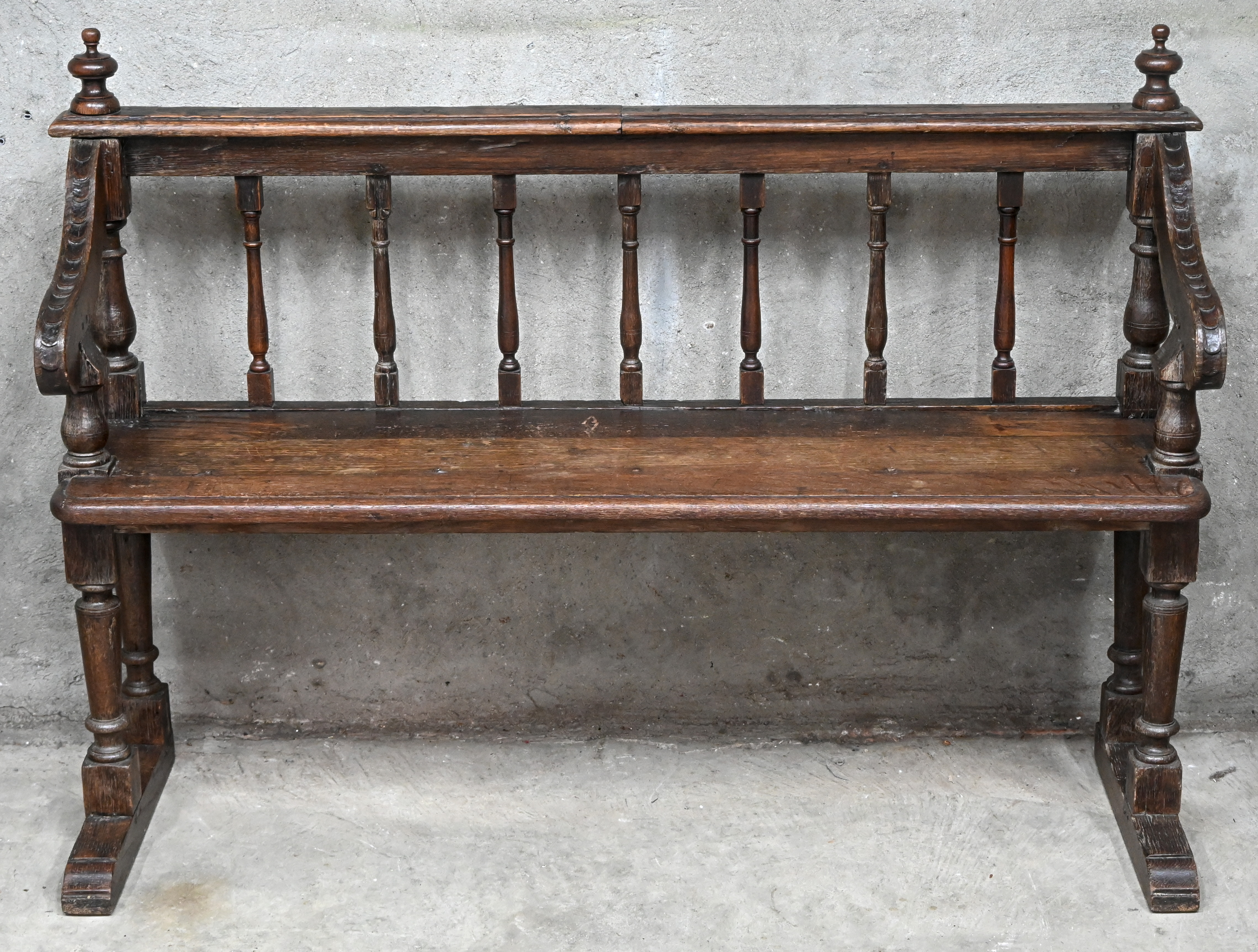 Een antieke massief houten bank, met gesculpteerde armleuningen en gedraaide spijlen in de rug Een antieke massief houten bank, met gesculpteerde armleuningen en gedraaide spijlen in de rug.