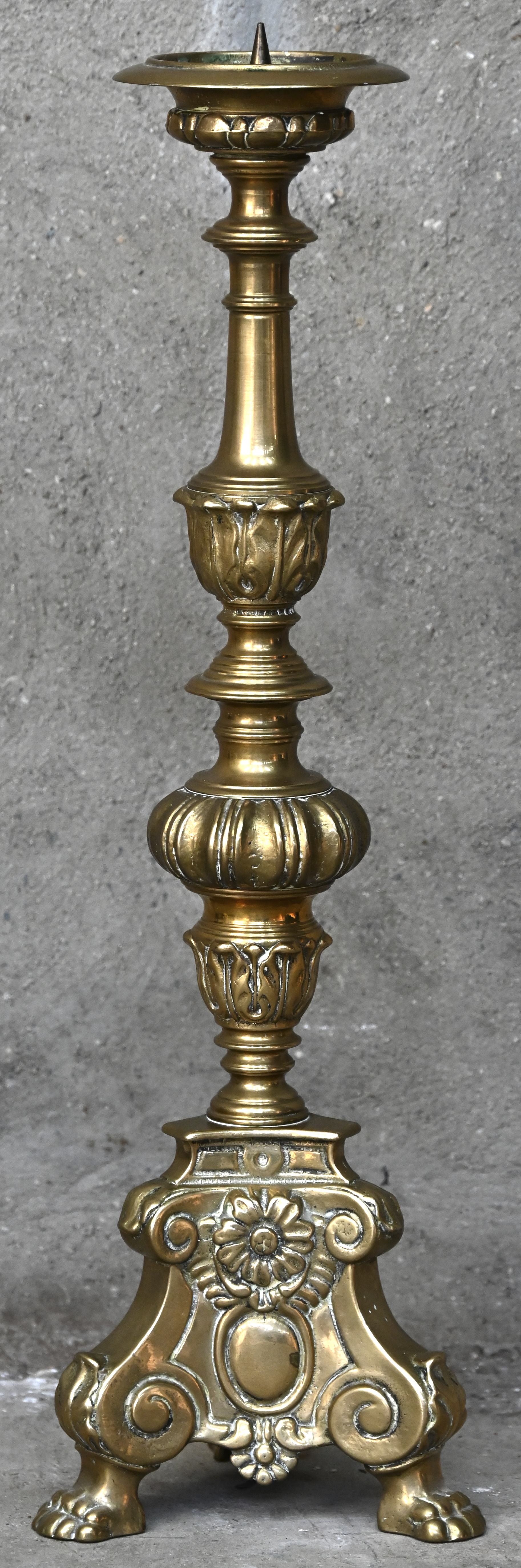 Een massieve messingen kerkkandelaar in barokke stijl. Driehoekig voetstuk op drie pootjes Een massieve messingen kerkkandelaar in barokke stijl. Driehoekig voetstuk op drie pootjes.