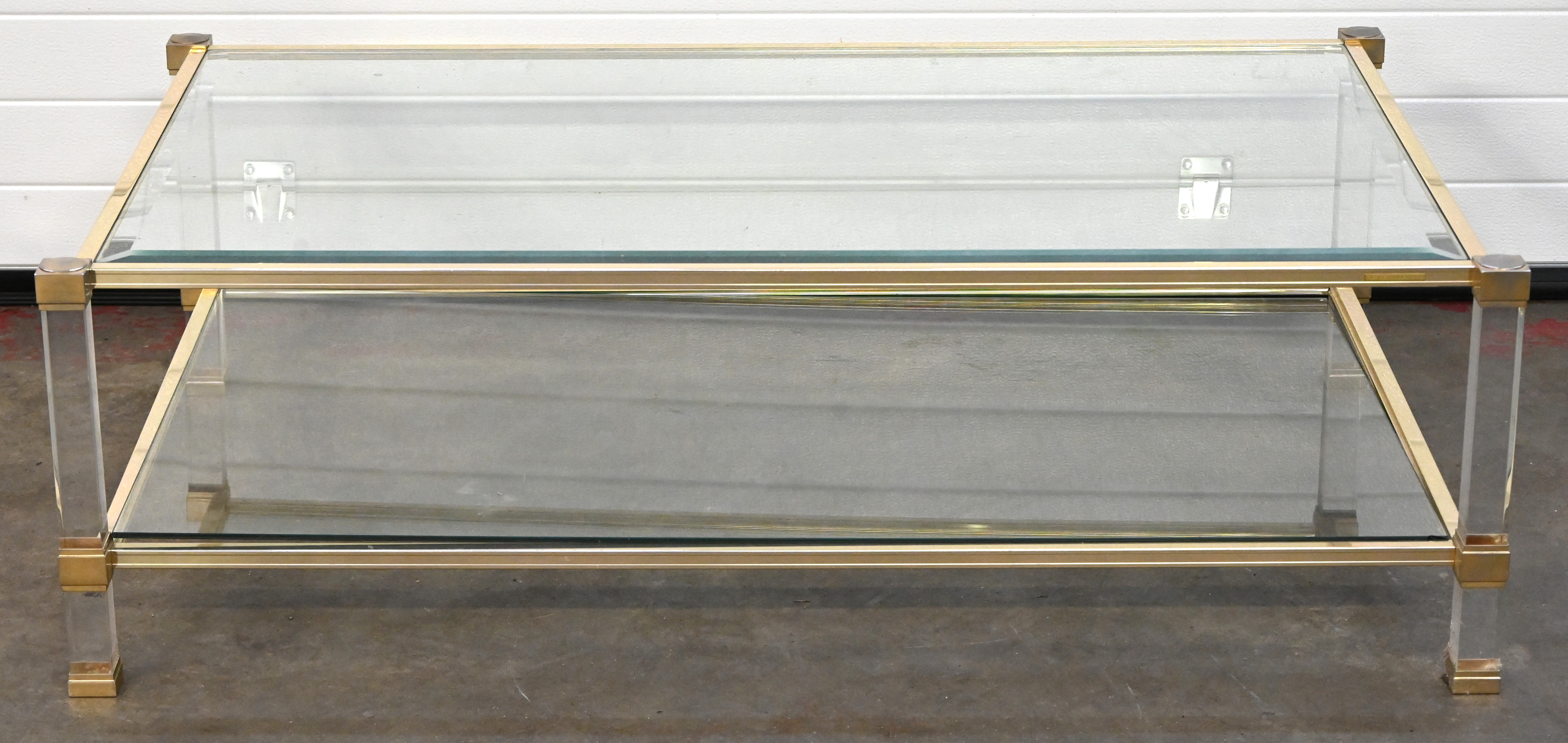 Een rechthoekige vintage salontafel, messing, glas en plexiglas, gemerkt Pierre Vandel. Het onderste glazen blad met kleine schade aan de hoek Een rechthoekige vintage salontafel, messing, glas en plexiglas, gemerkt Pierre Vandel. Het onderste glazen blad met kleine schade aan de hoek.