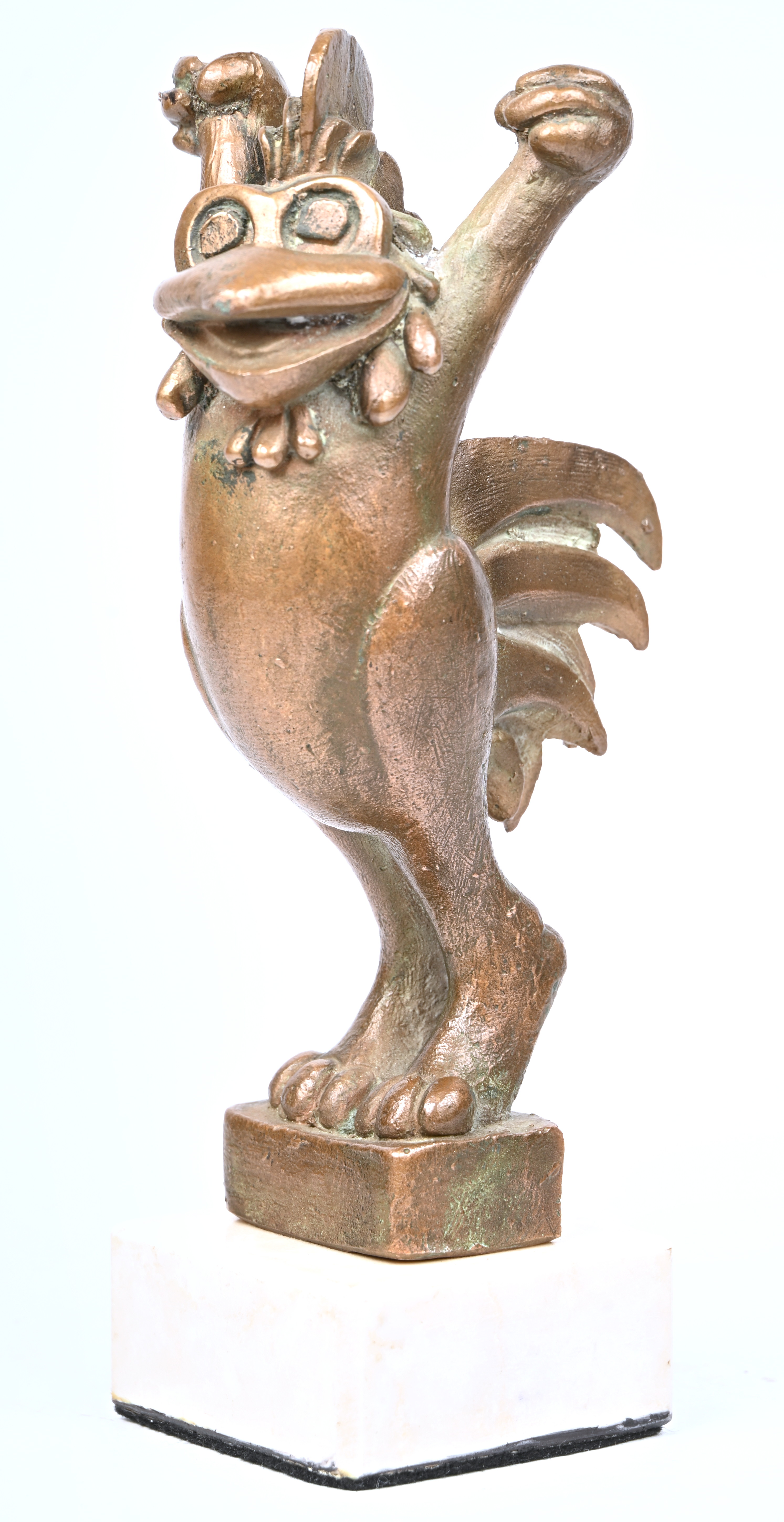 Een bronzen beeldje van een cartooneske haan op wit marmeren sokkeltje Een bronzen beeldje van een cartooneske haan op wit marmeren sokkeltje.