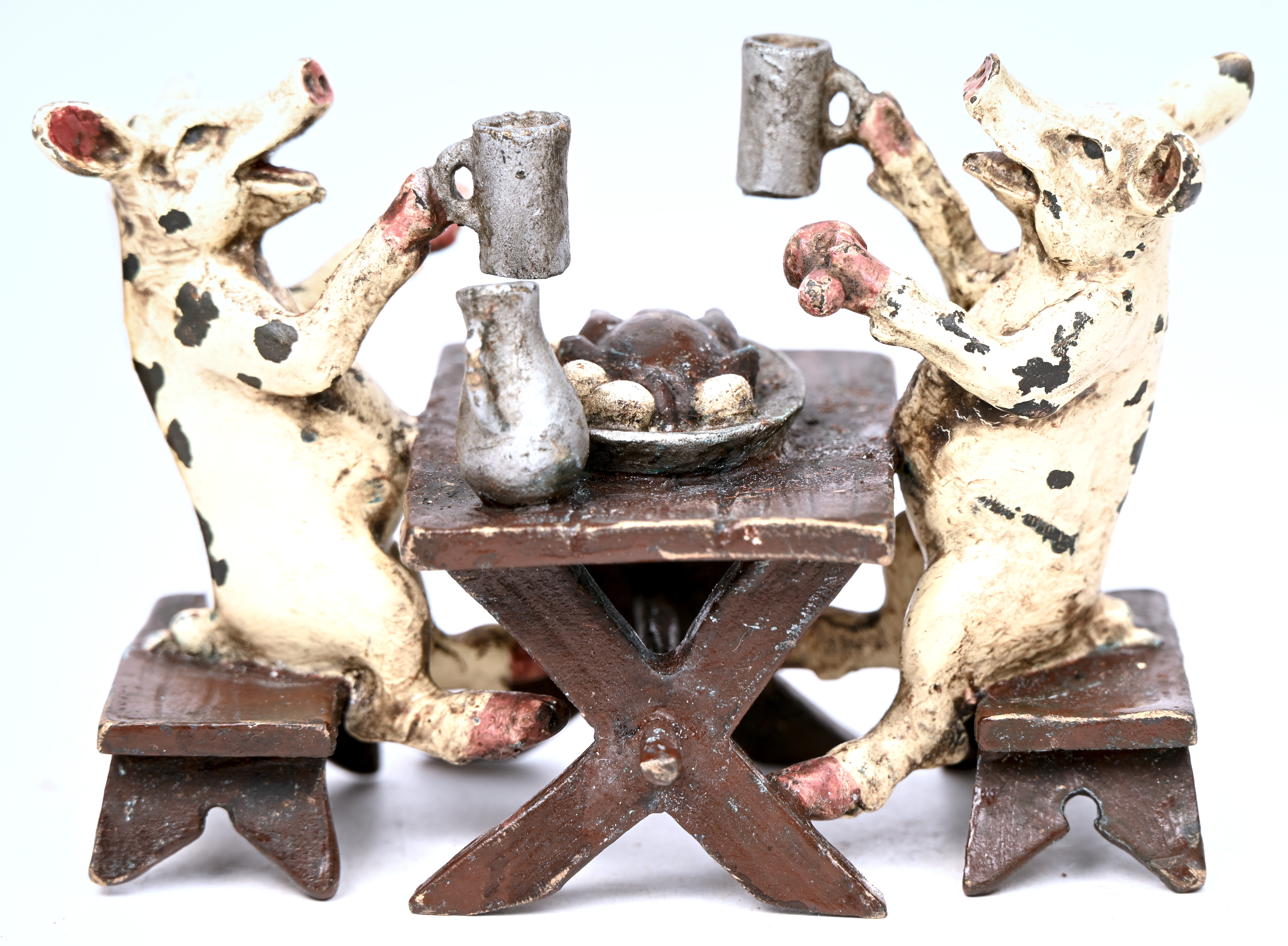 Twee polychrome bronzen varkentjes aan de feestdis Twee polychrome bronzen varkentjes aan de feestdis.