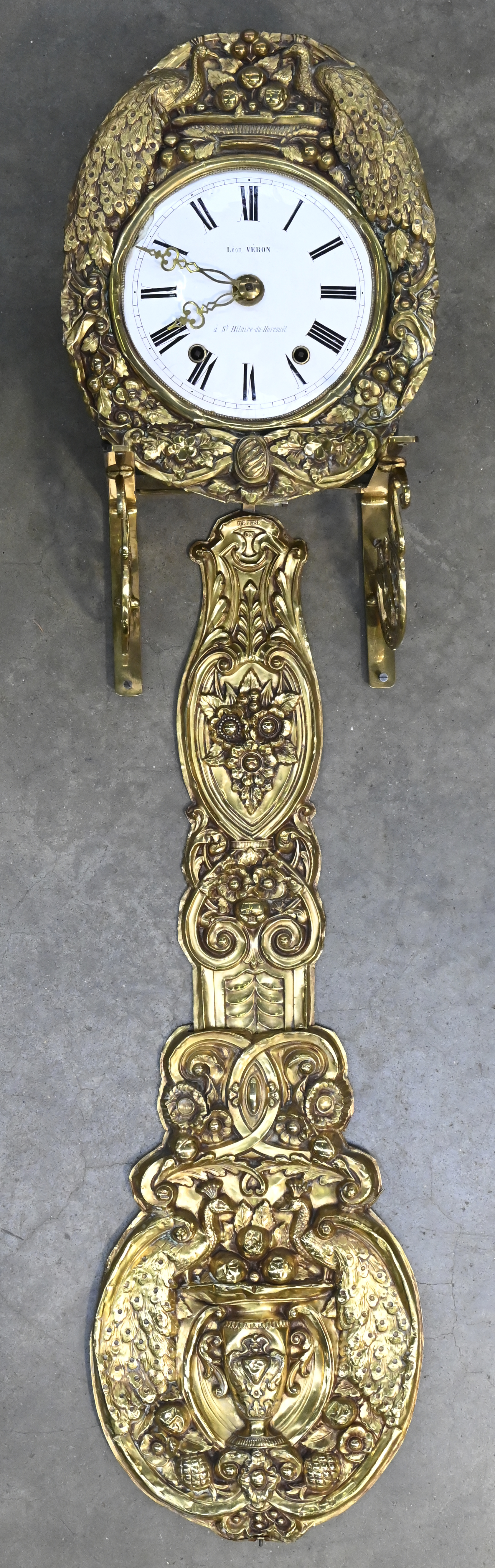 Een comptoise klok gemerkt op de émaille wijzerplaat: Léon Véron, à St. Hilaire-de-Harcouét, Dinanderie omranding en slinger met pauwen in het decor. Schade aan het émail. Met wandhouder Een comptoise klok gemerkt op de émaille wijzerplaat: Léon Véron, à St. Hilaire-de-Harcouét, Dinanderie omranding en slinger met pauwen in het decor. Schade aan het émail. Met wandhouder.