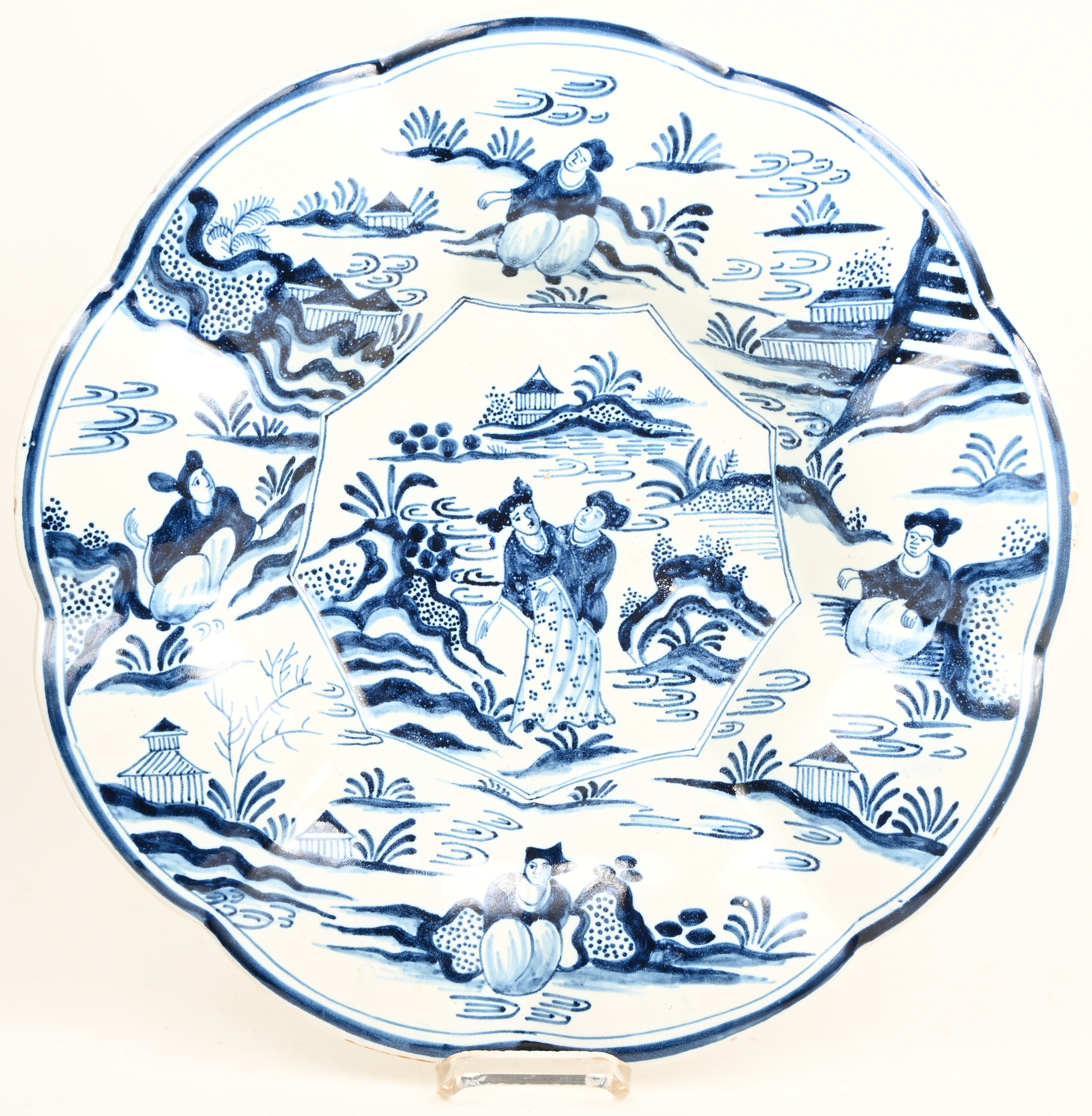 Een blauw-wit Delfts aardewerken plooischotel met diverse figuren en landschap in het decor Een blauw-wit Delfts aardewerken plooischotel met diverse figuren en landschap in het decor.