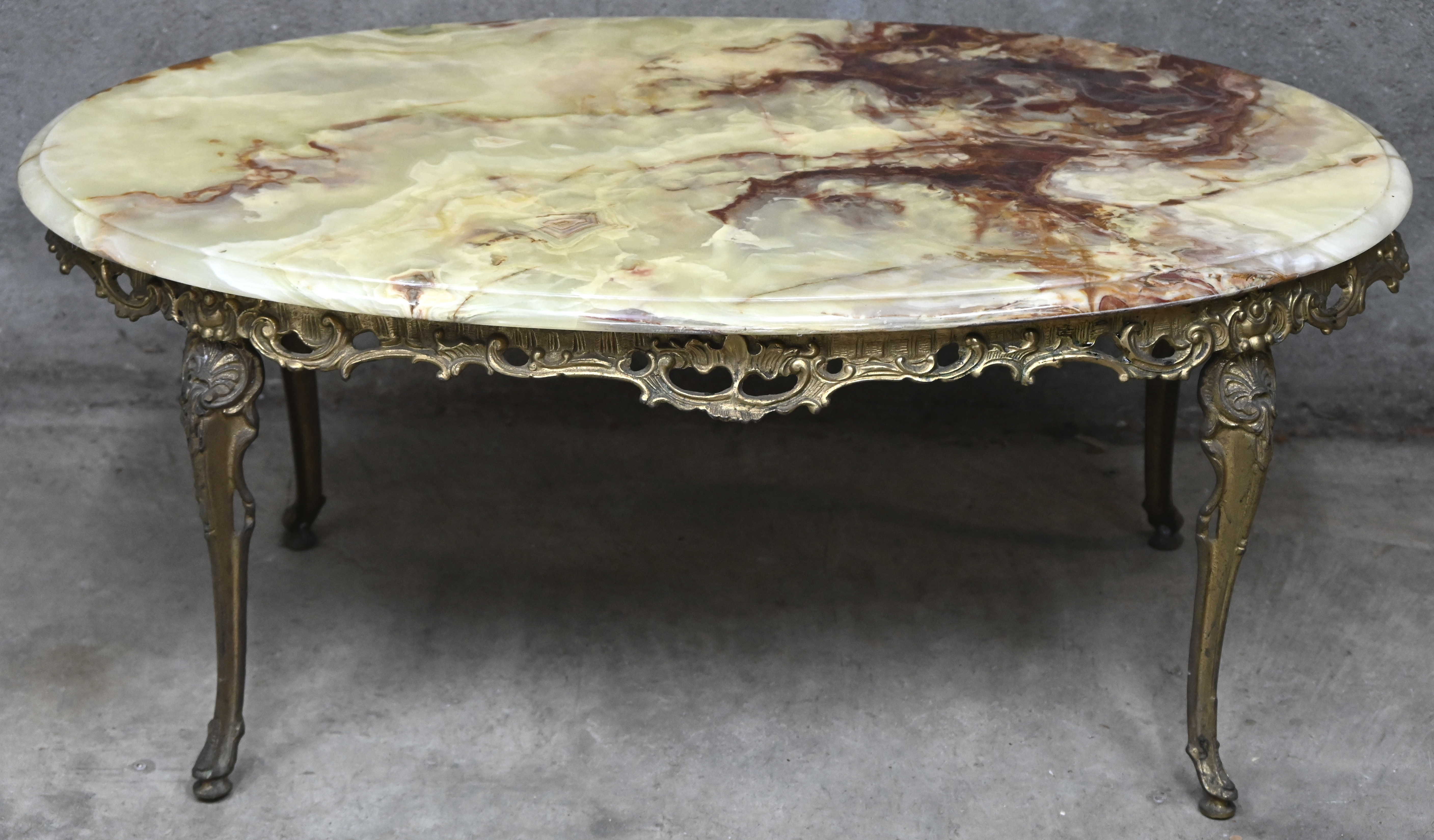 Een ovalen salontafel in Louis XV-stijl, messing met onyx blad Een ovalen salontafel in Louis XV-stijl, messing met onyx blad.