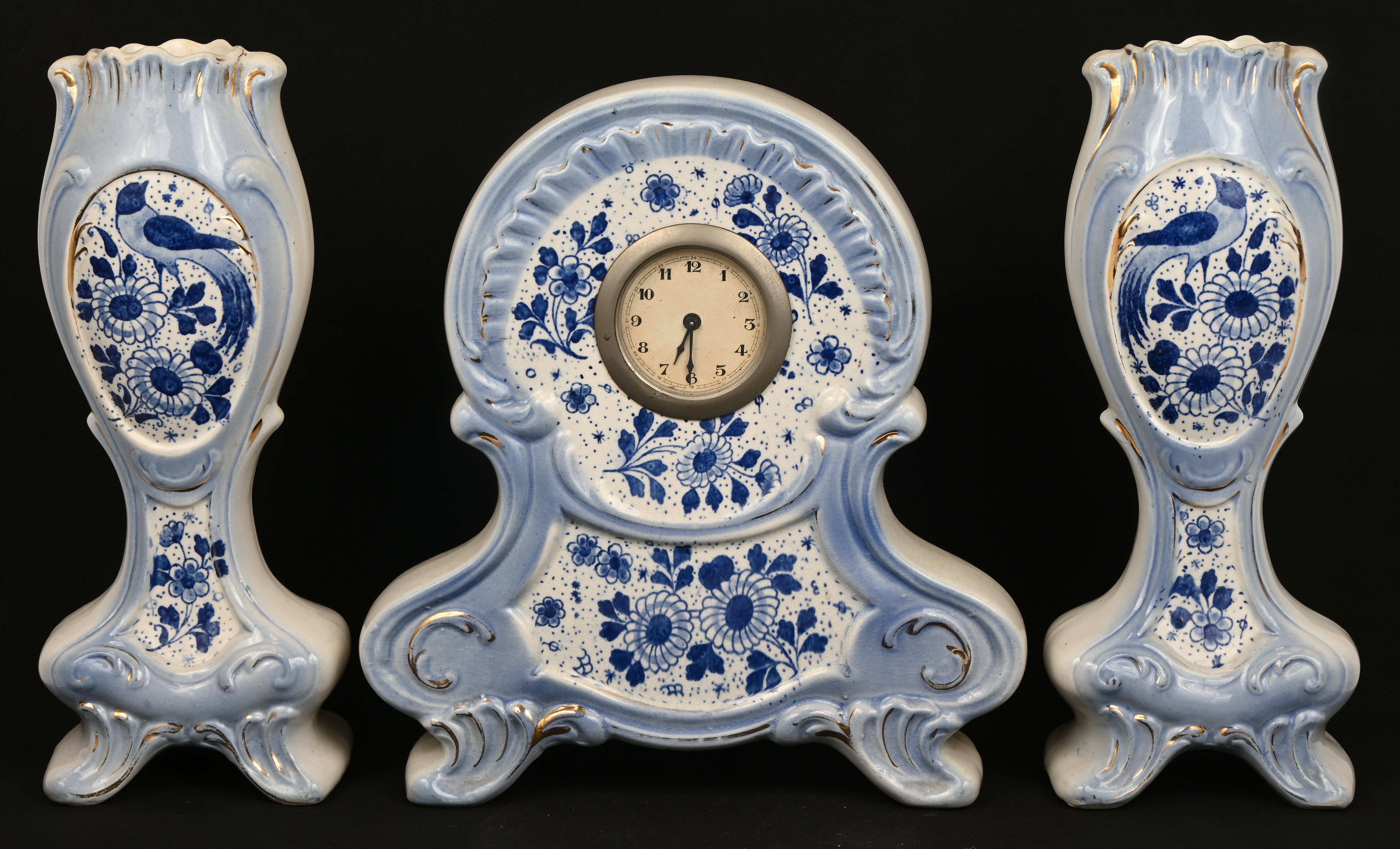 Een driedelig klokstelletje van blauw en wit aardewerk. Onderaan gemerkt: AMC Een driedelig klokstelletje van blauw en wit aardewerk. Onderaan gemerkt: AMC.