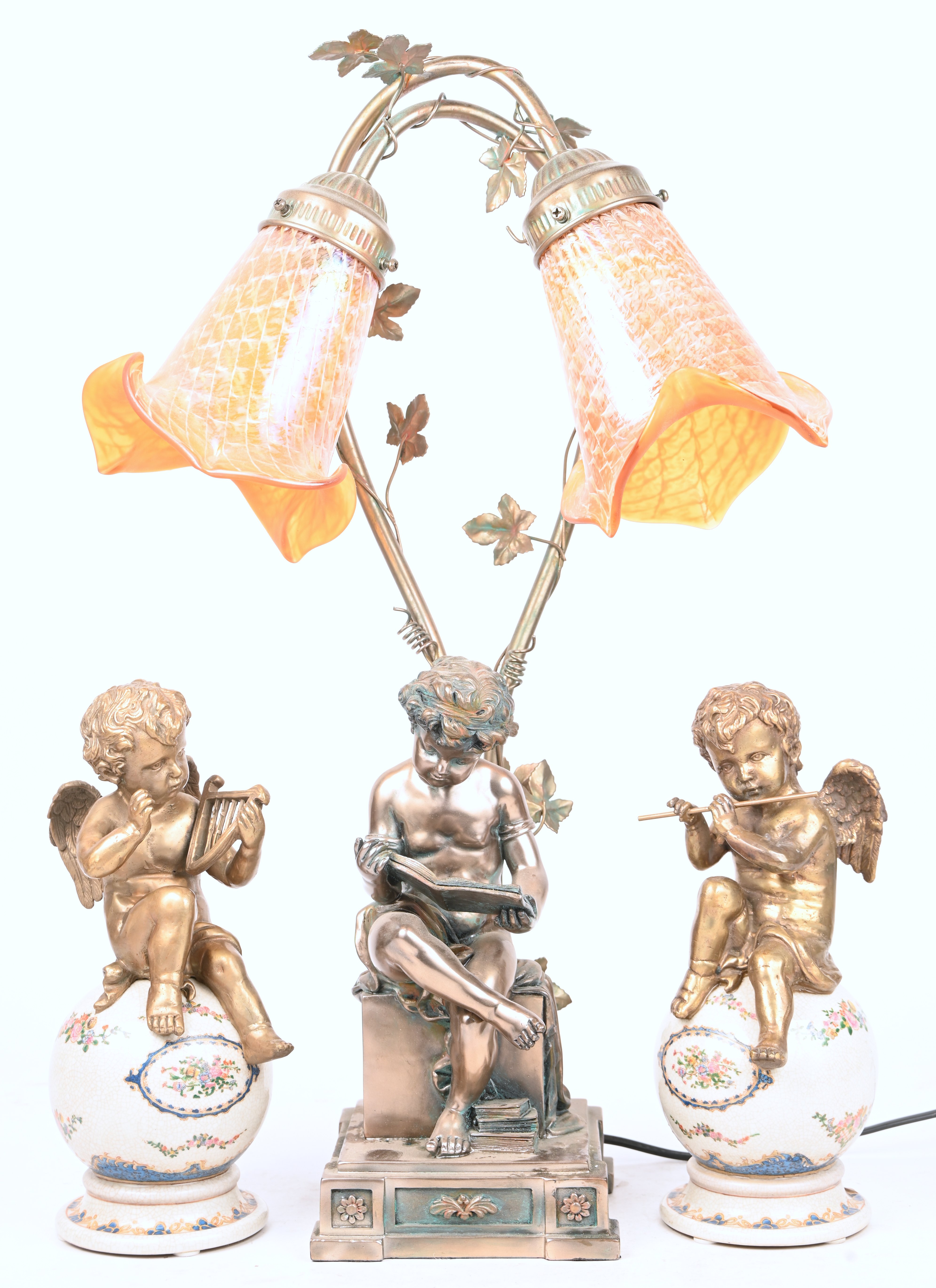 Een tafellamp met lezende putti, toegevoegd 2 muzicerende engelen gezeten op een porseleinen bol Een tafellamp met lezende putti, toegevoegd 2 muzicerende engelen gezeten op een porseleinen bol.