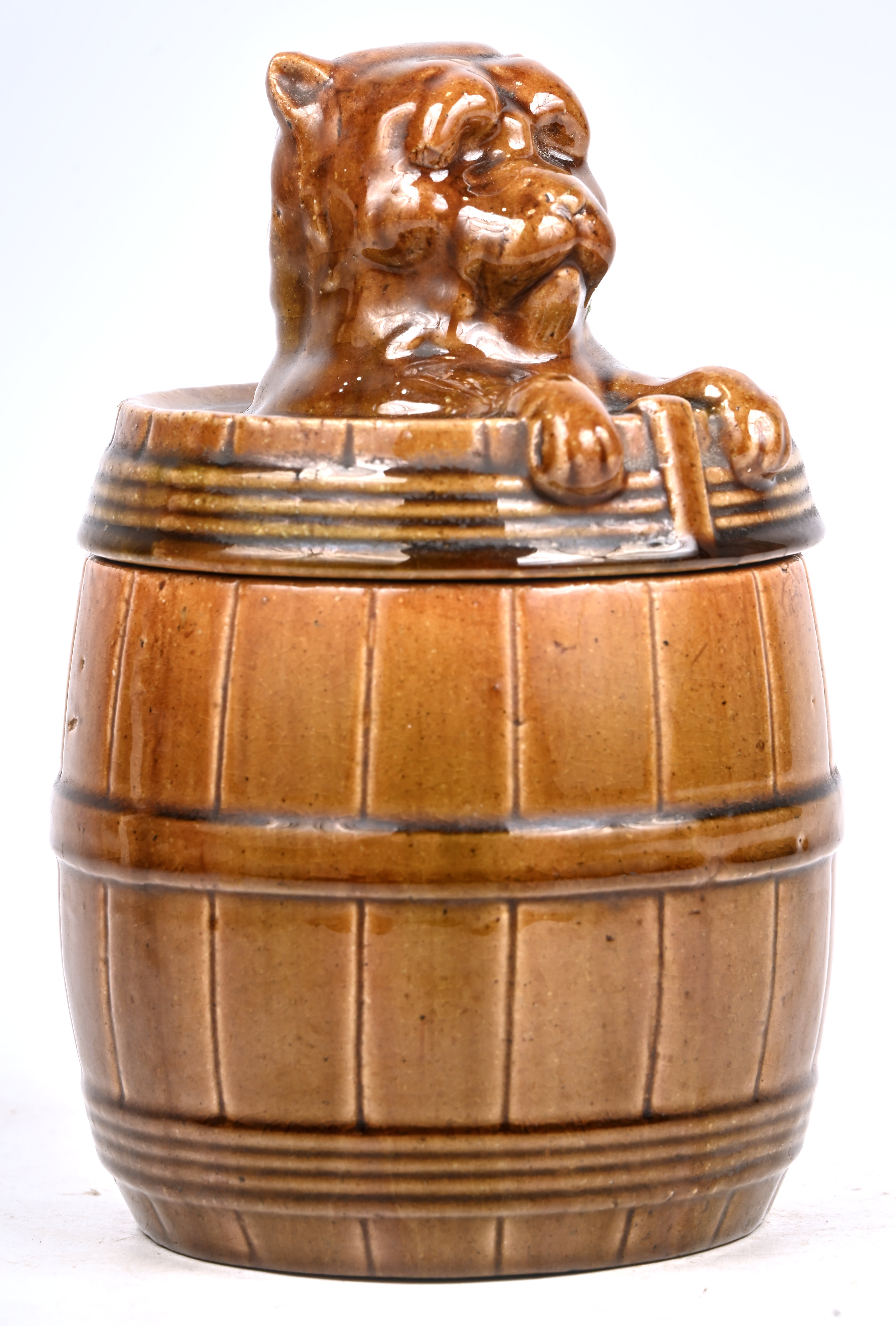 Een tabakspot van Vlaams aardewerk, in de vorm van een hond in een ton. Met schilferschade aan de rand Een tabakspot van Vlaams aardewerk, in de vorm van een hond in een ton. Met schilferschade aan de rand.