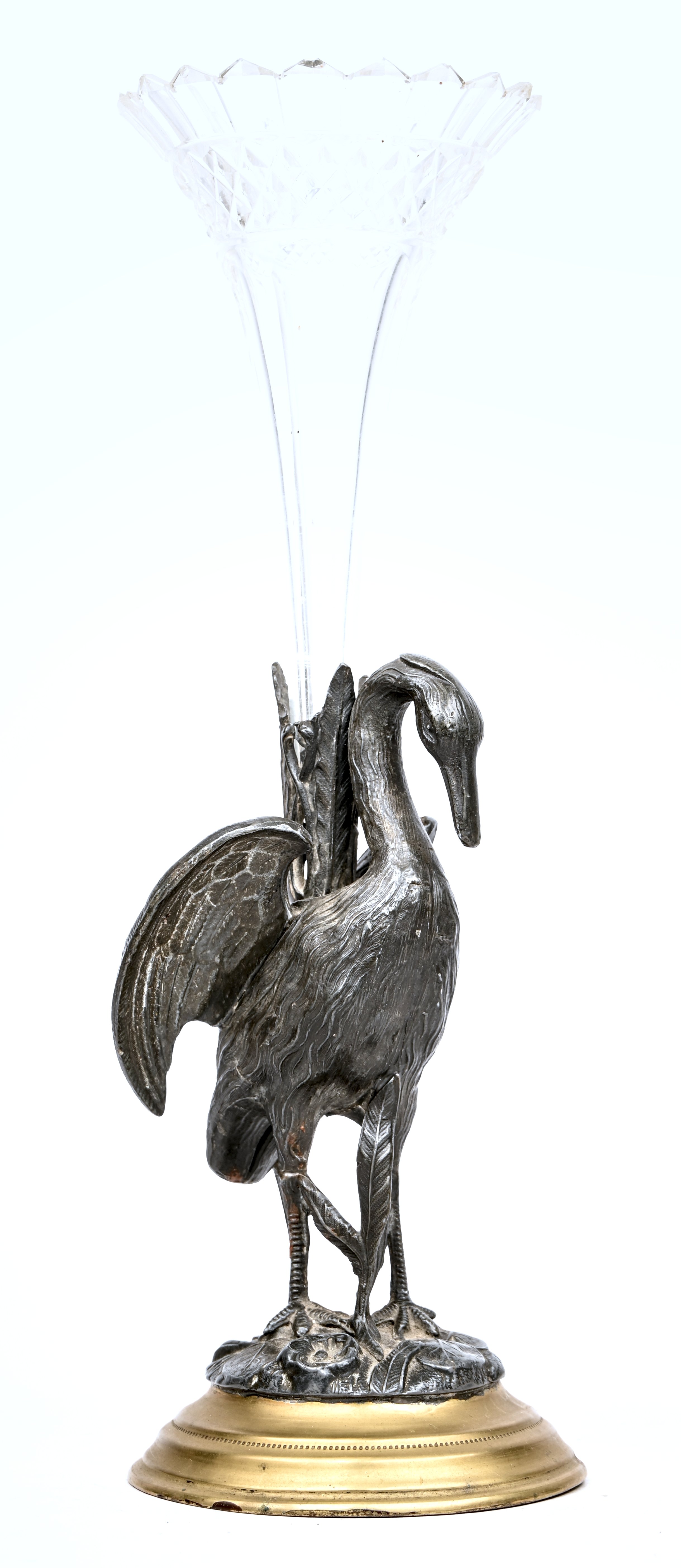 Een glazen siervaas gedragen door een waadvogel, van gepatineerd zamac. Met een herstelling aan beide poten. Niet gemerkt Een glazen siervaas gedragen door een waadvogel, van gepatineerd zamac. Met een herstelling aan beide poten. Niet gemerkt.