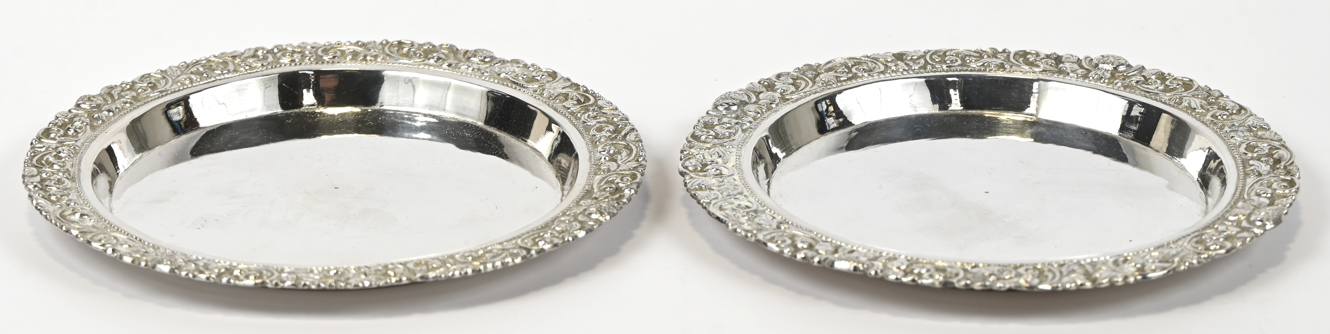 Een paar flessenonderzetters van zilver met gedreven florale fries. Indonesisch werk Een paar flessenonderzetters van zilver met gedreven florale fries. Indonesisch werk. 295 g AR28-30