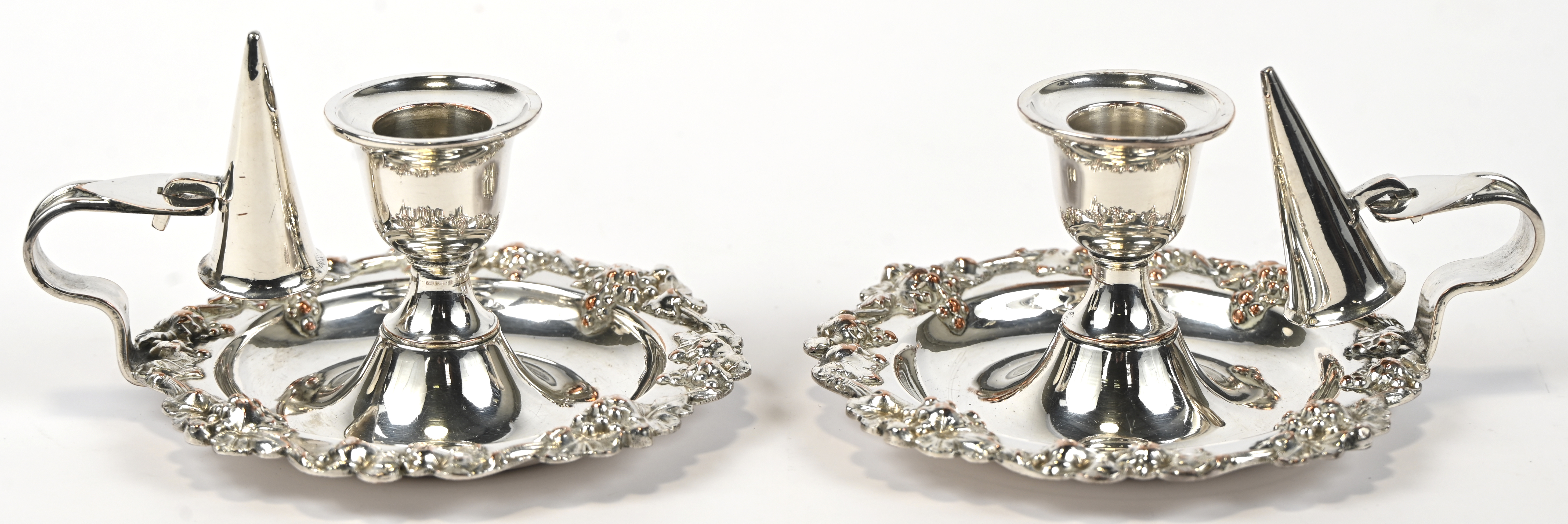 Een paar kaarsenpannetjes met snuiters van verzilverd metaal. Mooie gedreven druivenranden Een paar kaarsenpannetjes met snuiters van verzilverd metaal. Mooie gedreven druivenranden. AR18