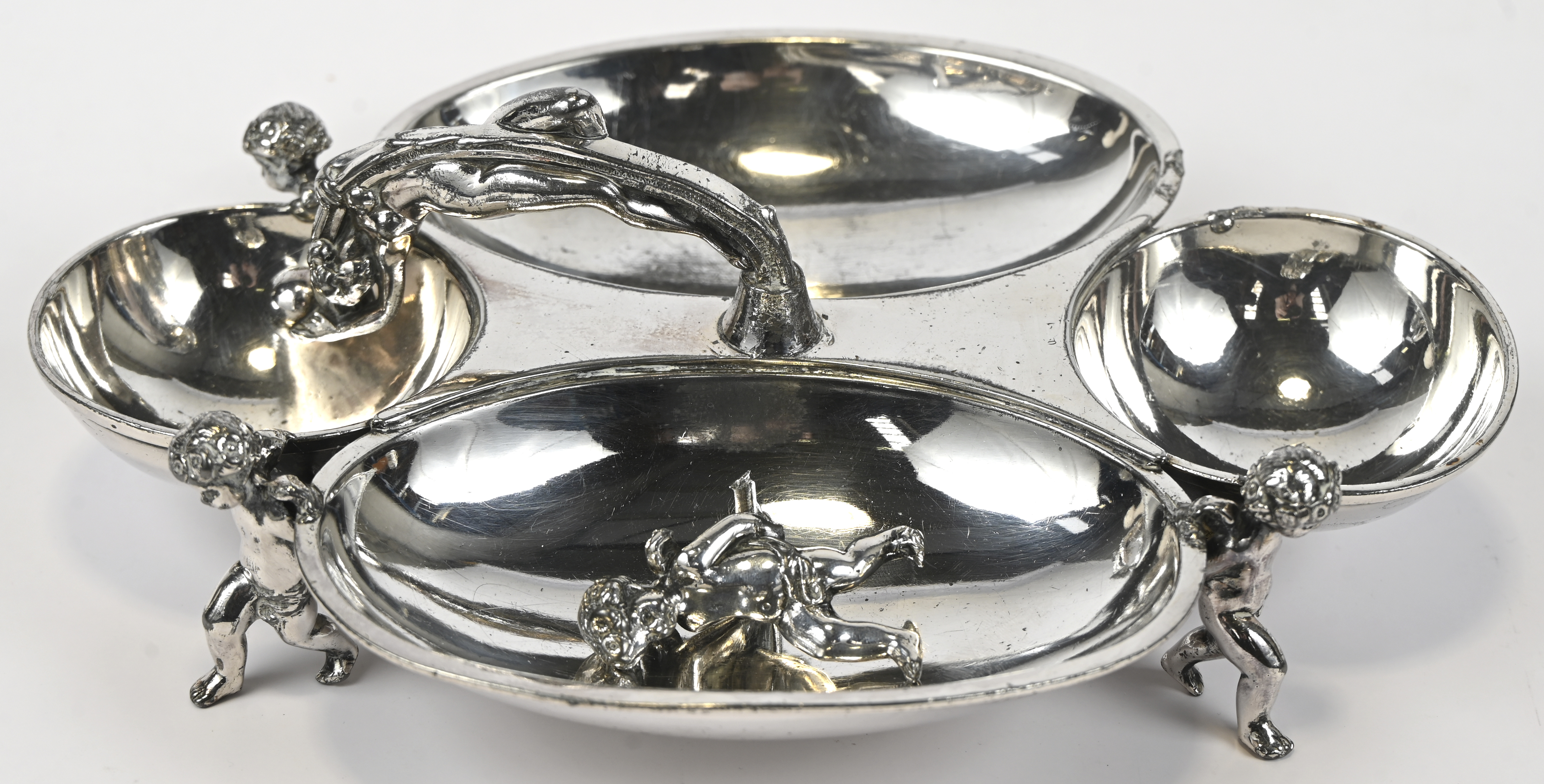 Een hors d’oeuvreschaaltje met drie coupes, gedragen door putti en handvat in de vorm van een naakt. Eén putto opnieuw te solderen Een hors d’oeuvreschaaltje met drie coupes, gedragen door putti en handvat in de vorm van een naakt. Eén putto opnieuw te solderen. AR19