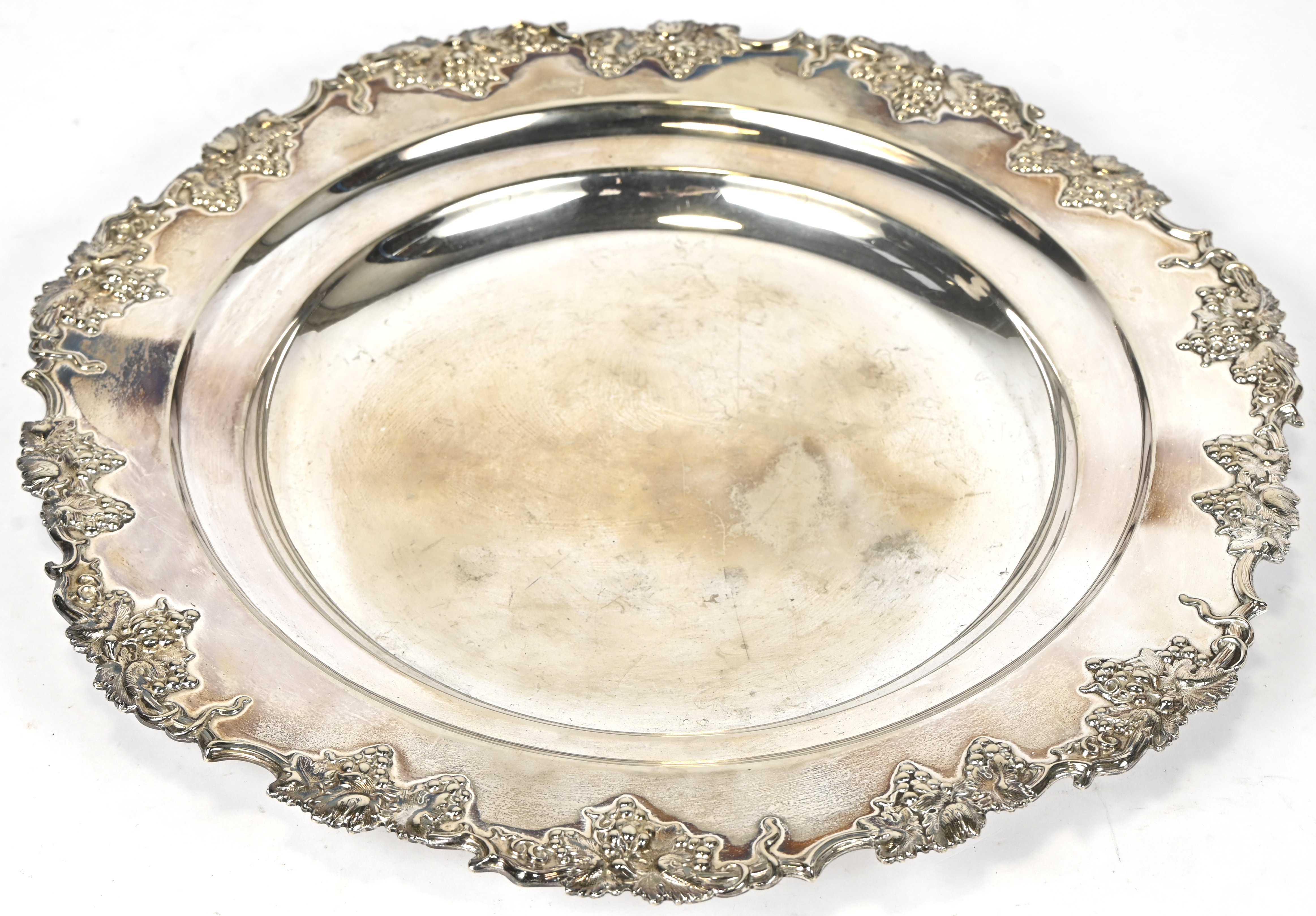 Een ronde schotel met een gedreven druivenrand. Gemerkt E.P.en genummerd Een ronde schotel met een gedreven druivenrand. Gemerkt E.P.en genummerd.