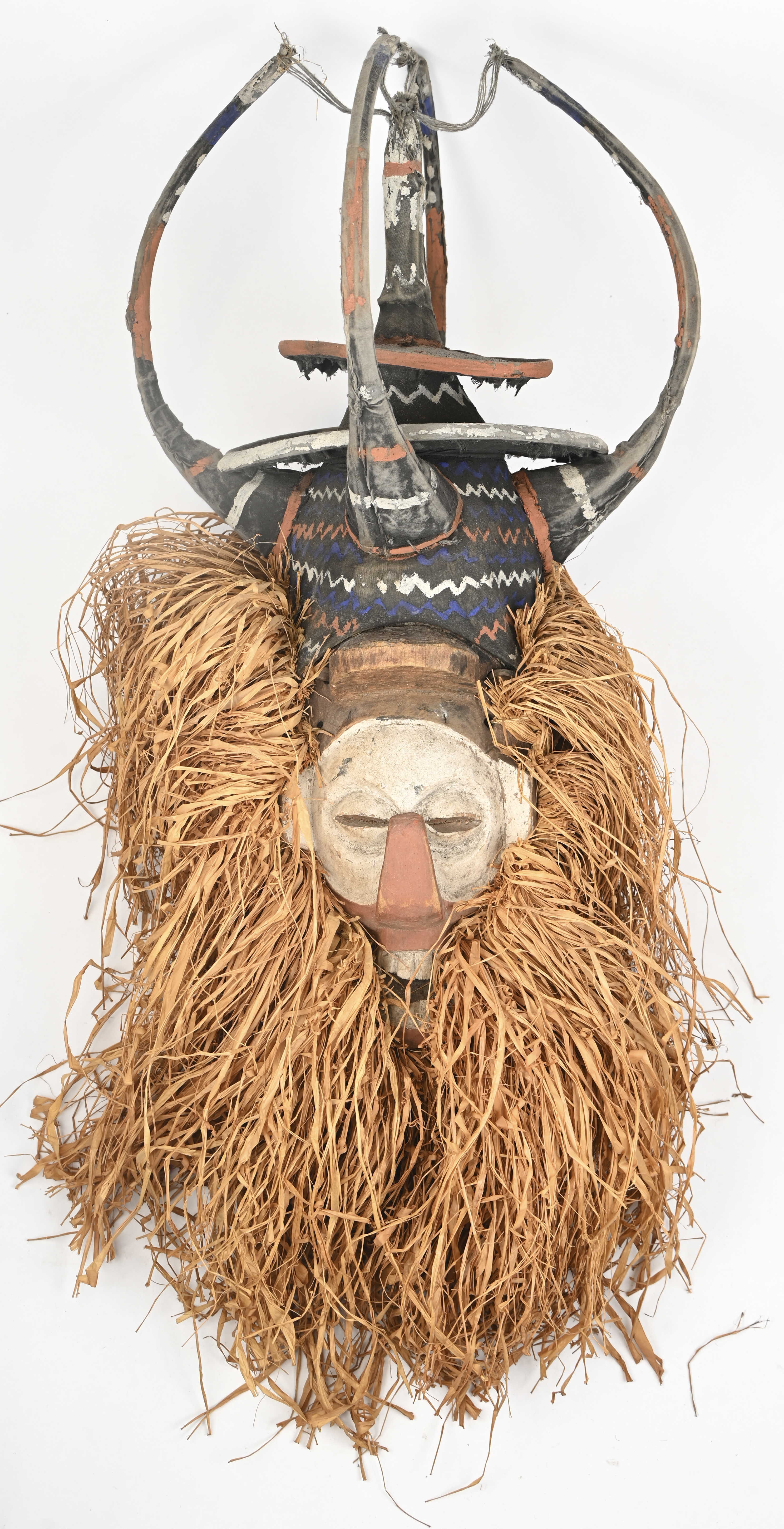 Een helmmasker van gebeeldhouwd en gebeitst hout. Voor initiatieritueel. Yaka, Kongo. voorzien van strooien tooi Een helmmasker van gebeeldhouwd en gebeitst hout. Voor initiatieritueel. Yaka, Kongo. voorzien van strooien tooi.