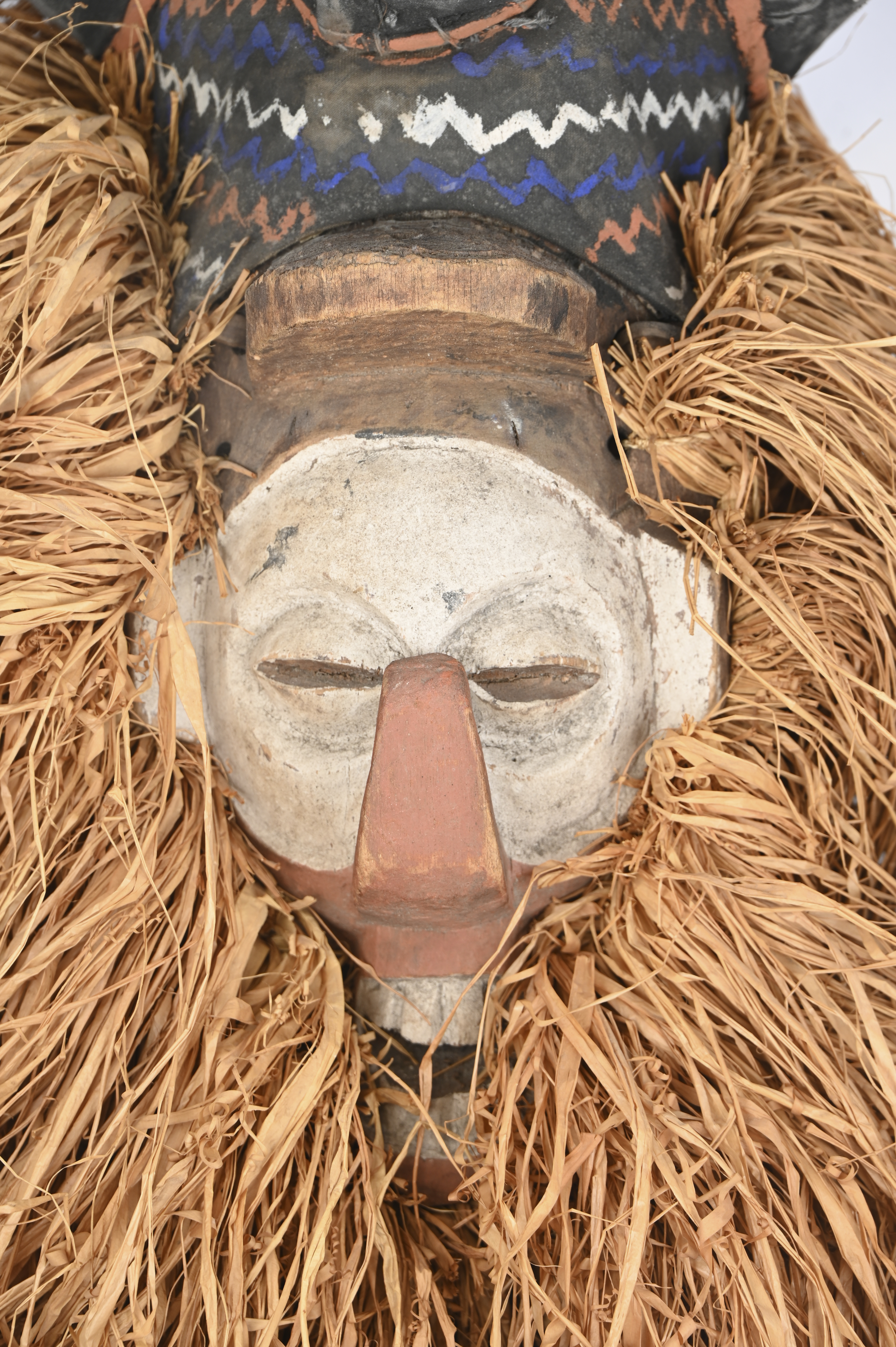 Een helmmasker van gebeeldhouwd en gebeitst hout. Voor initiatieritueel. Yaka, Kongo. voorzien van strooien tooi Een helmmasker van gebeeldhouwd en gebeitst hout. Voor initiatieritueel. Yaka, Kongo. voorzien van strooien tooi.