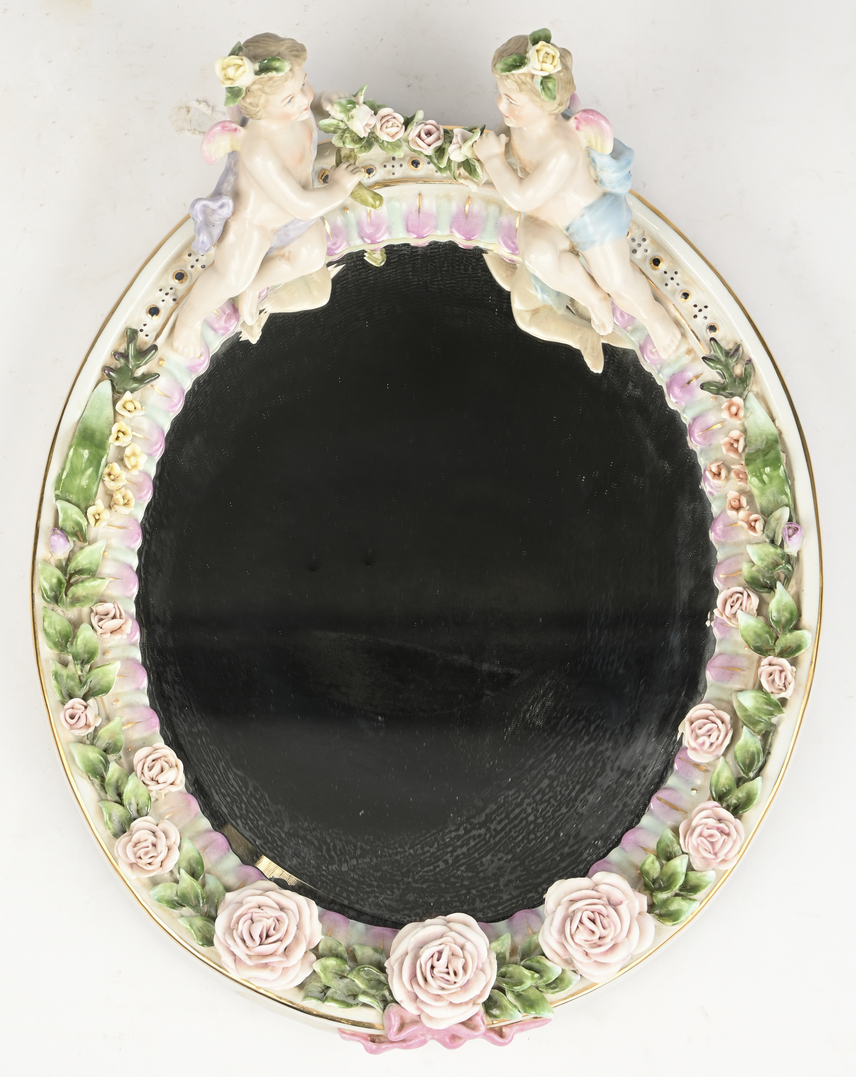 Een spiegeltje in porseleinen kader, met bloemen en engeltjes gedecoreerd. Gemerkt met gekruiste zwaarden boven een R Een spiegeltje in porseleinen kader, met bloemen en engeltjes gedecoreerd. Gemerkt met gekruiste zwaarden boven een R.