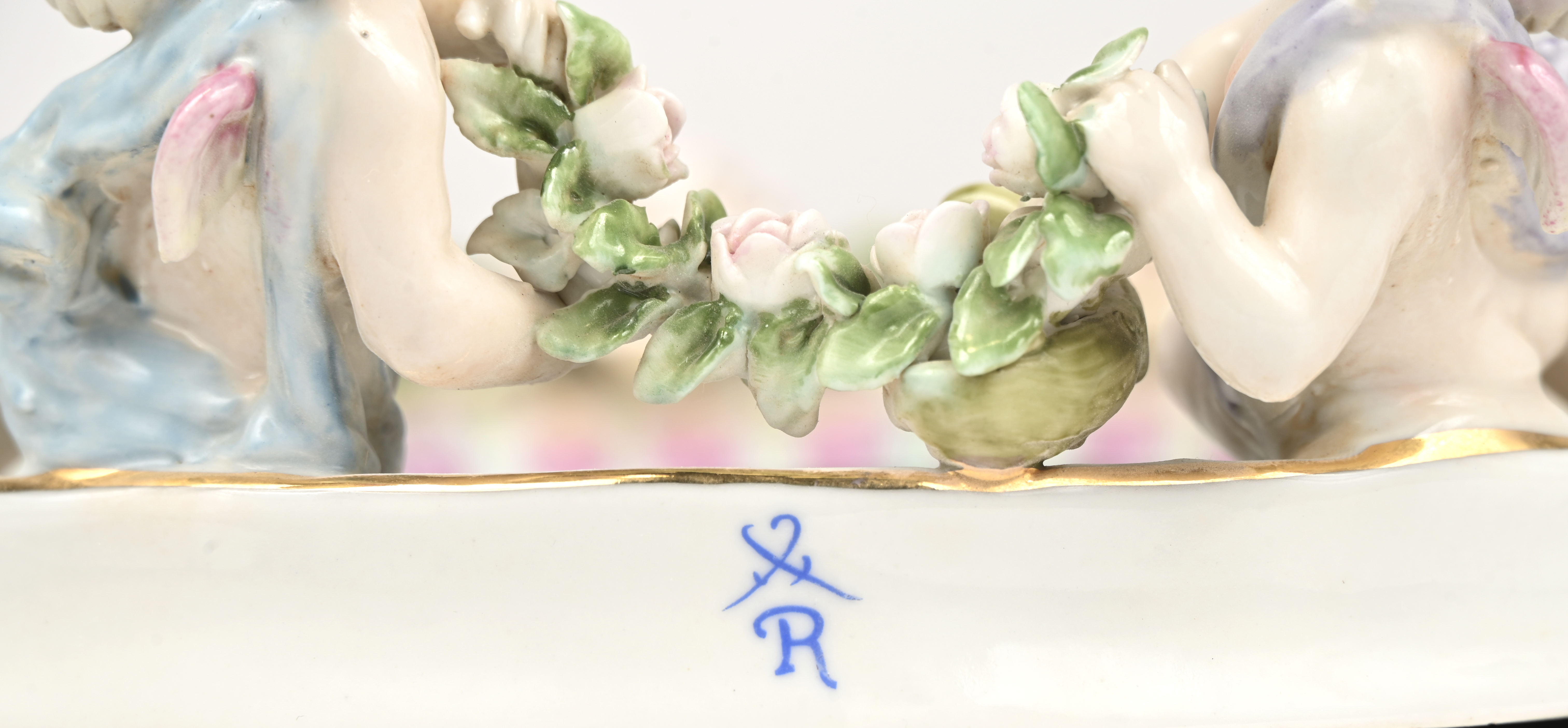 Een spiegeltje in porseleinen kader, met bloemen en engeltjes gedecoreerd. Gemerkt met gekruiste zwaarden boven een R Een spiegeltje in porseleinen kader, met bloemen en engeltjes gedecoreerd. Gemerkt met gekruiste zwaarden boven een R.