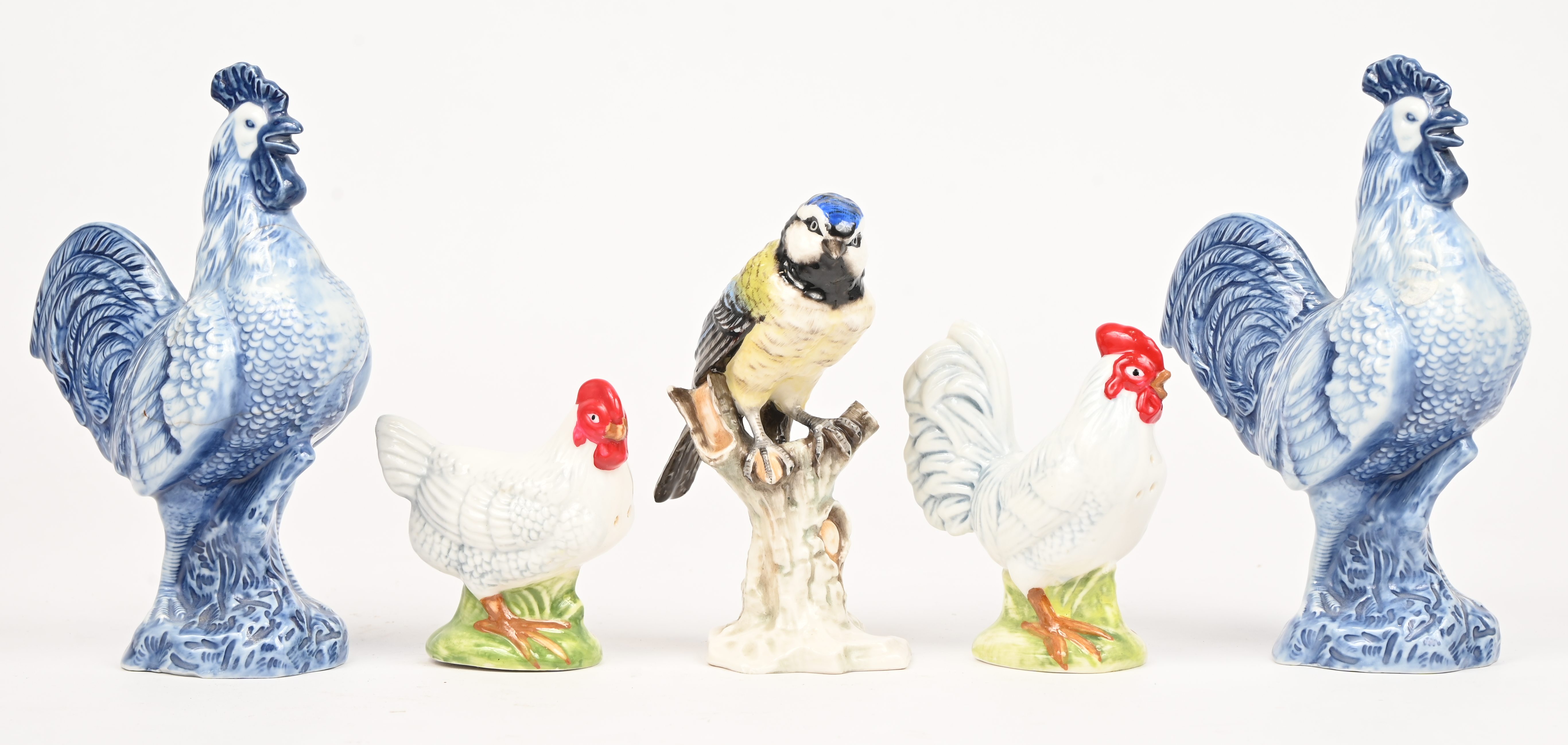 Een lot van 5 porseleinen beeldjes, een koolmeesje op stronk, 2 blauw-witte hanen waarvan 1 gelijmd en een peper- en zoutvaatje in de vorm van een kip en een haan Een lot van 5 porseleinen beeldjes, een koolmeesje op stronk, 2 blauw-witte hanen waarvan 1 gelijmd en een peper- en zoutvaatje in de vorm van een kip en een haan.